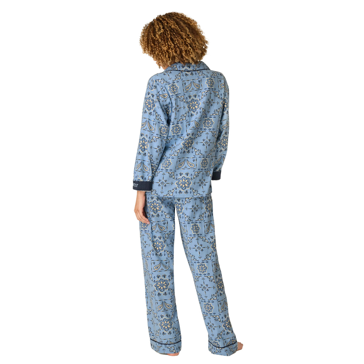 Model wearing PJ Salvage Howdy flannel pyjama set with blue floral paisley print and relaxed straight-leg pants, back view.
