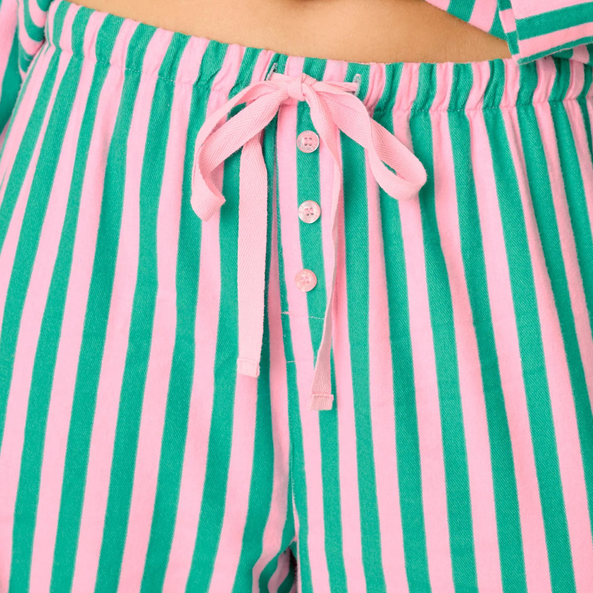 Close-up of pink and green striped flannel pajama pants featuring elastic waistband, pink drawstring and button fly.