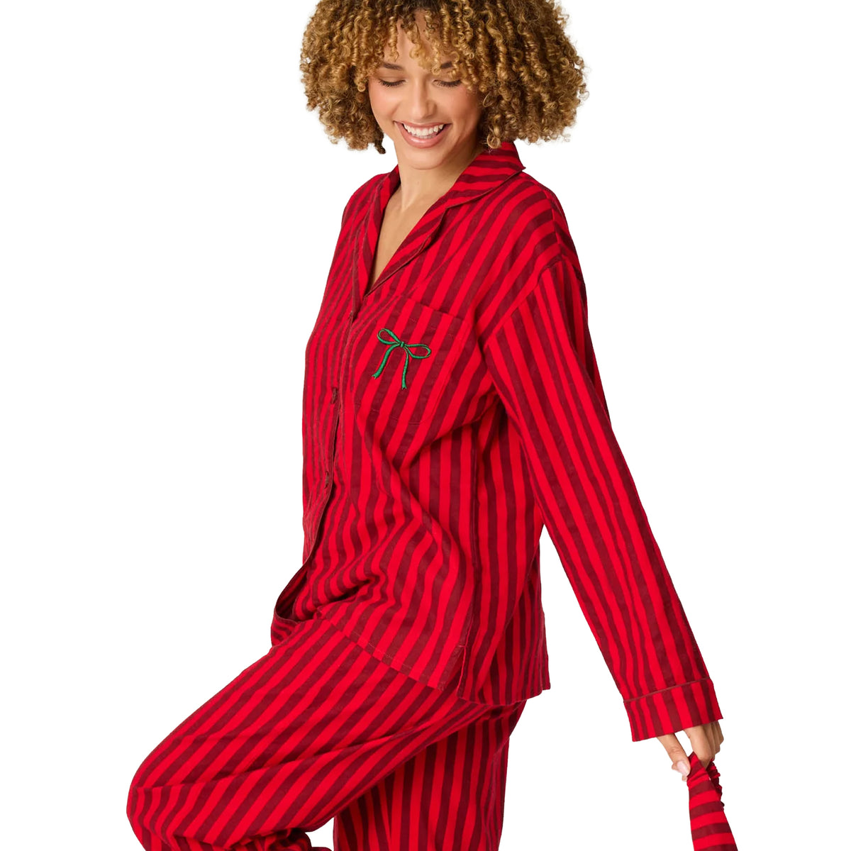 Model wearing red and burgundy striped flannel pajamas with green embroidered bow on chest pocket, side view.