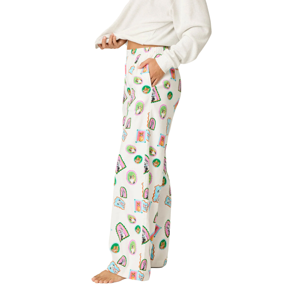 Side view of cream printed pajama pants with colorful dog and cat illustrations, relaxed wide-leg fit and side pocket.