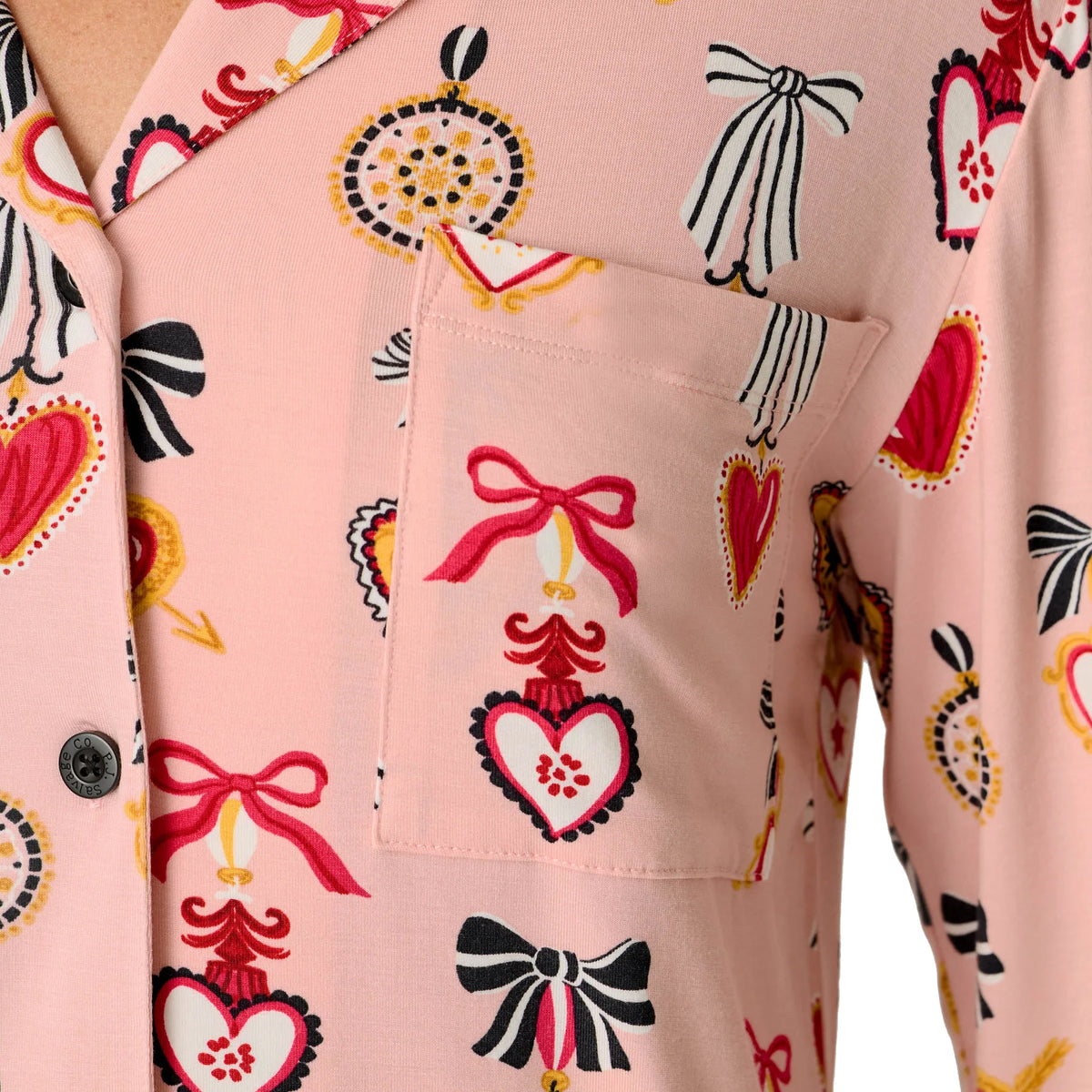 Close-up of PJ Salvage Hearts sleepshirt showing chest pocket and decorative red hearts, black bows and yellow accents on pink fabric.
