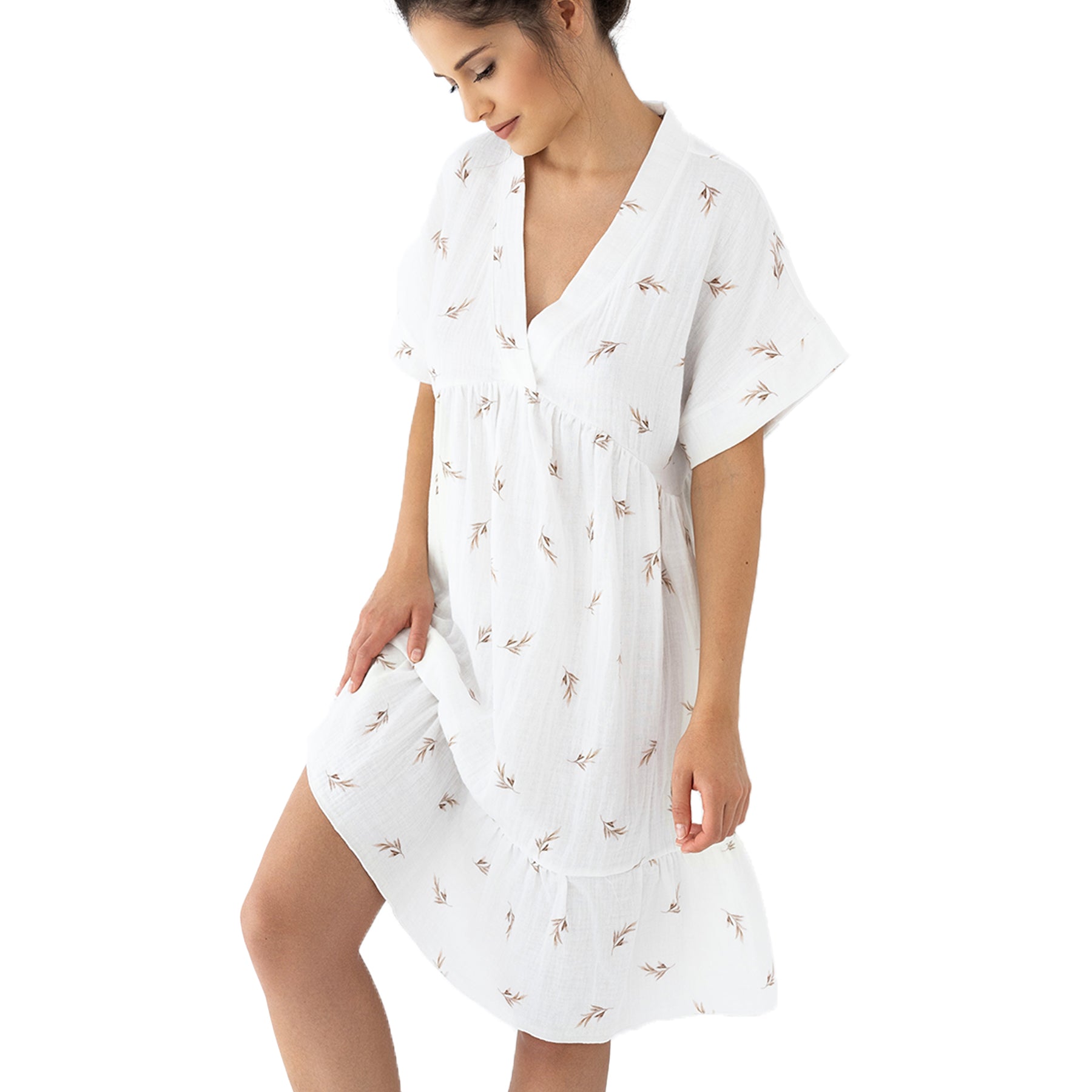 Woman in ivory muslin nightdress with taupe leaf print and V-neckline, gently holding the hem