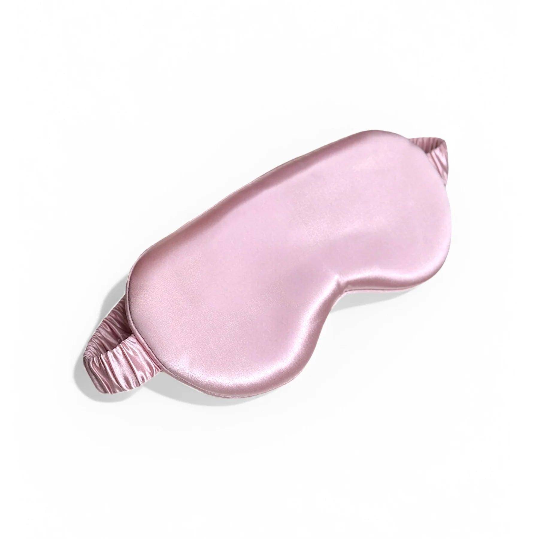 Pink silk eye mask with ruched elastic band, angled display.