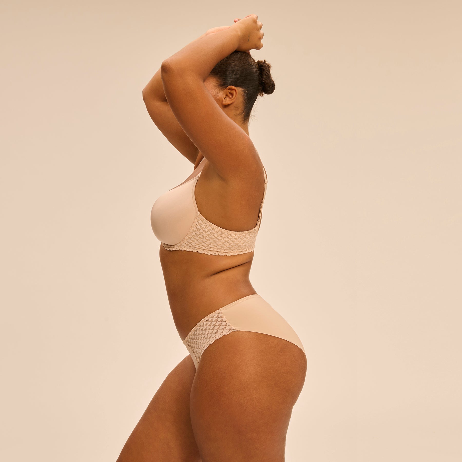 Bikini brief with lace hips in nude peau rose, side view on model.