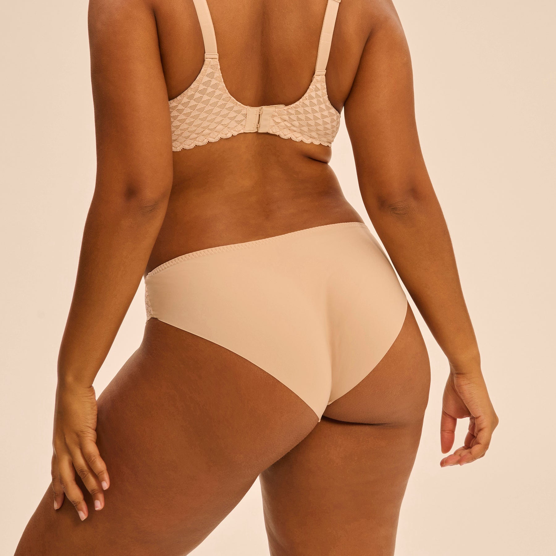Bikini brief with lace hips in nude peau rose, rear view on model.
