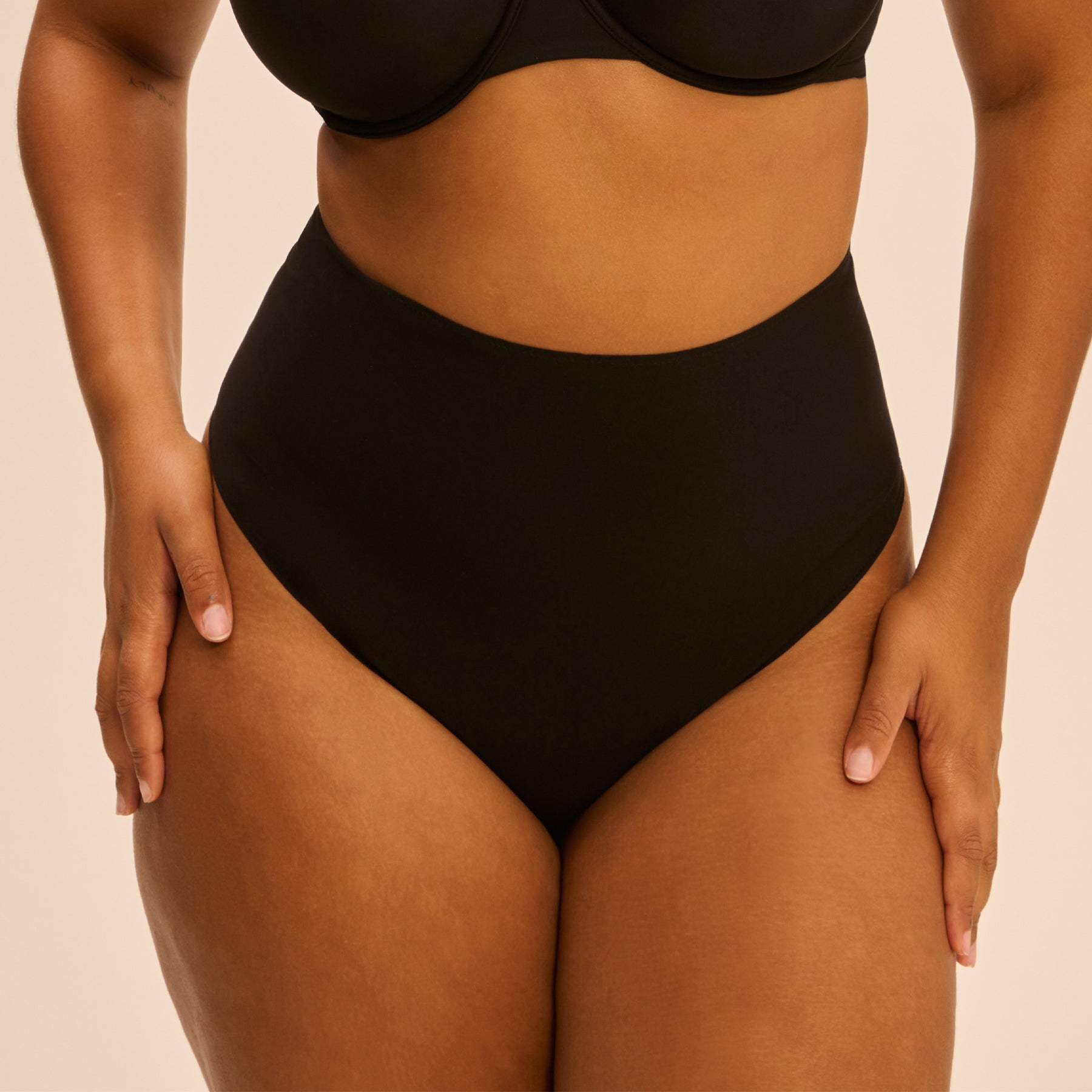 Plus-size model in Simone Pérèle black Story Control Thong - supportive high-rise thong showcasing curve-enhancing fit and clean front.