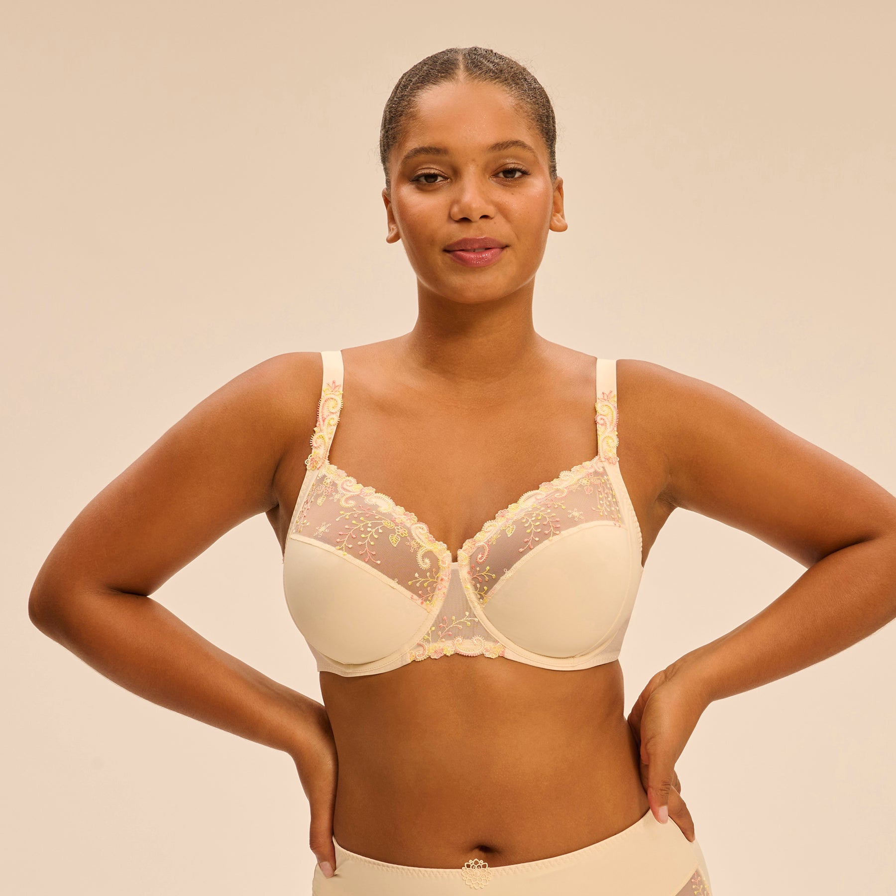 3 Part full cup bra in pale yellow peach pampa with contrast coral pink embroidery along the cups. Front view on model.
