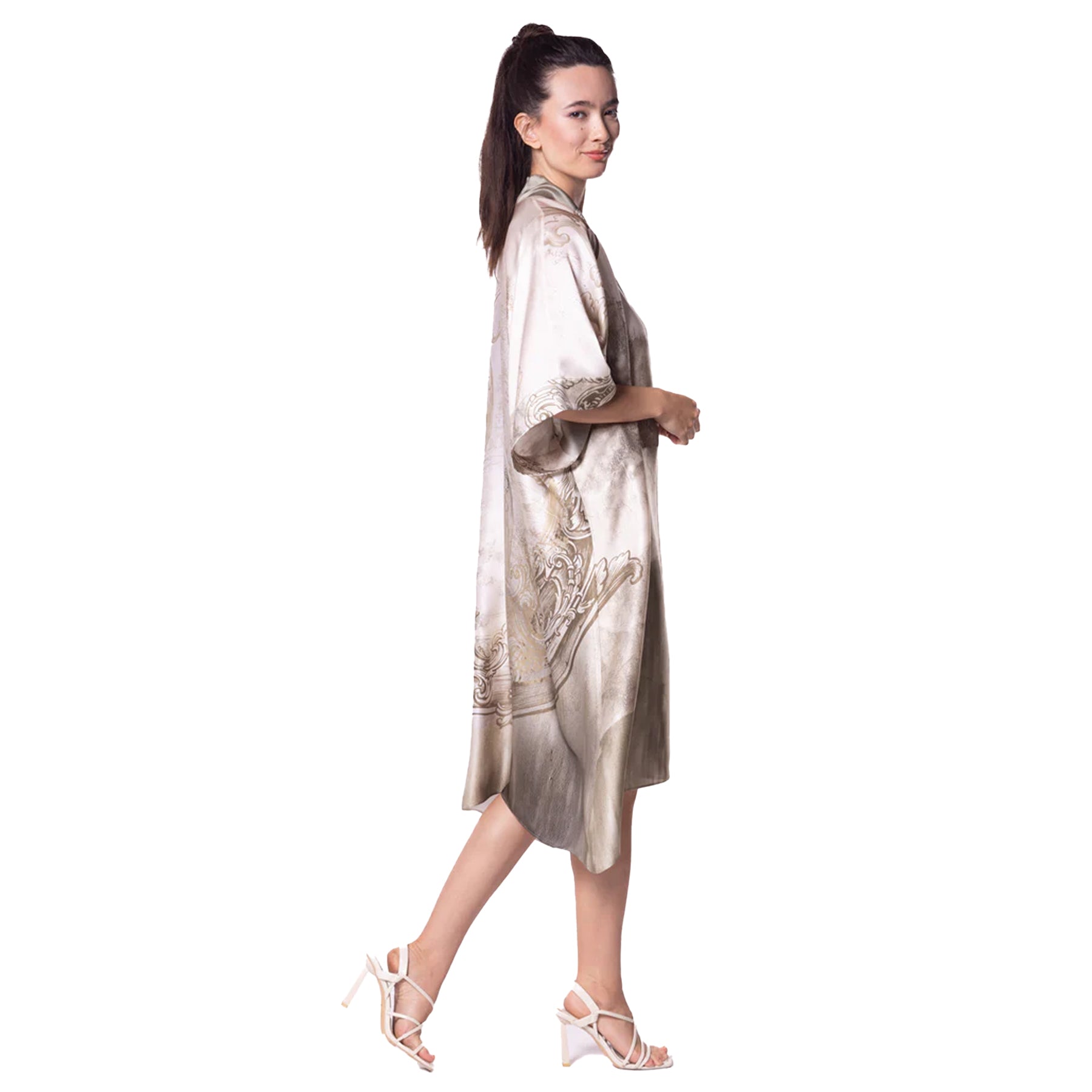 Side profile of a woman walking in a mid-length satin robe with sweeping baroque-style designs and subtle luster.