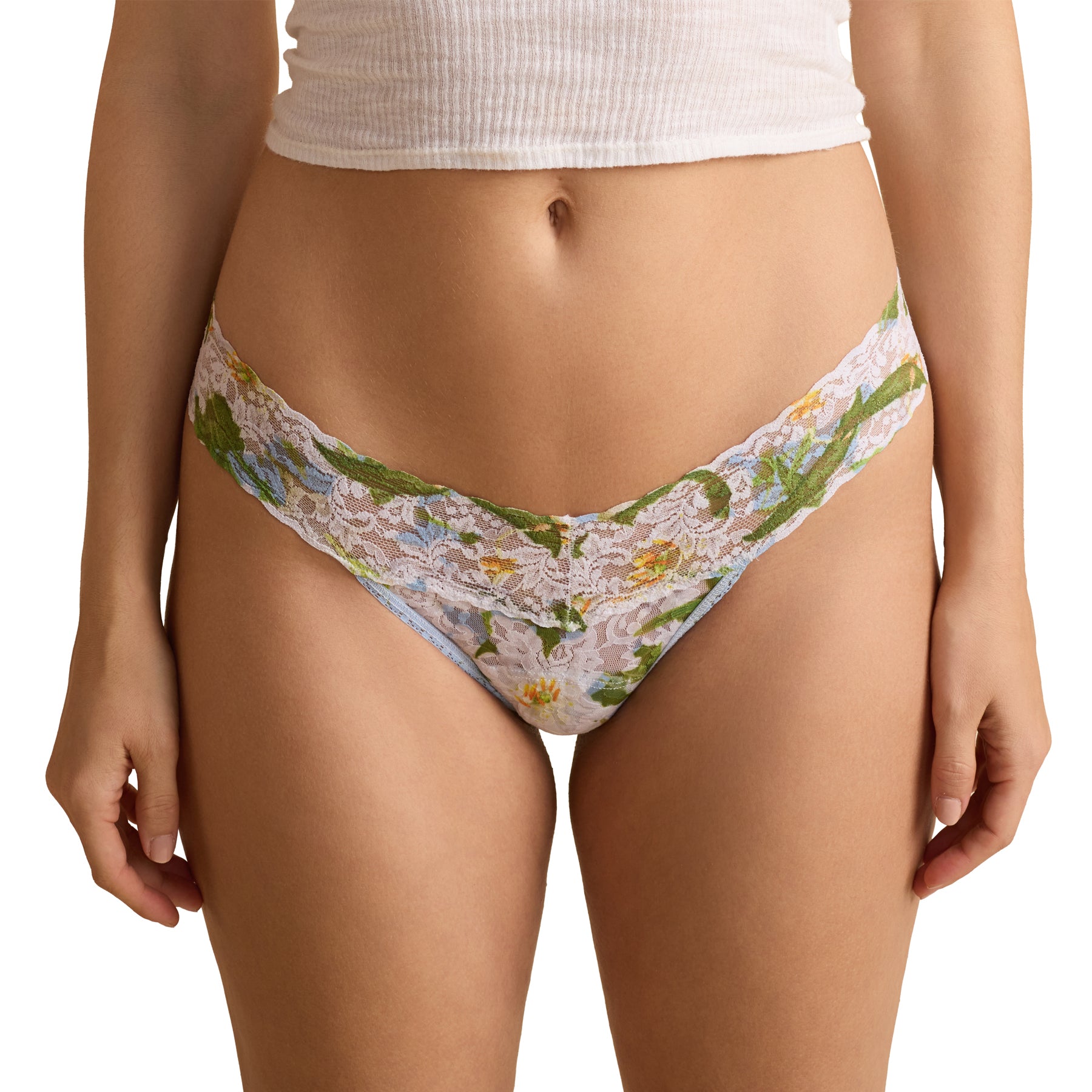 Front view of floral lace thong on model, white lace with green lily print and scalloped waistband