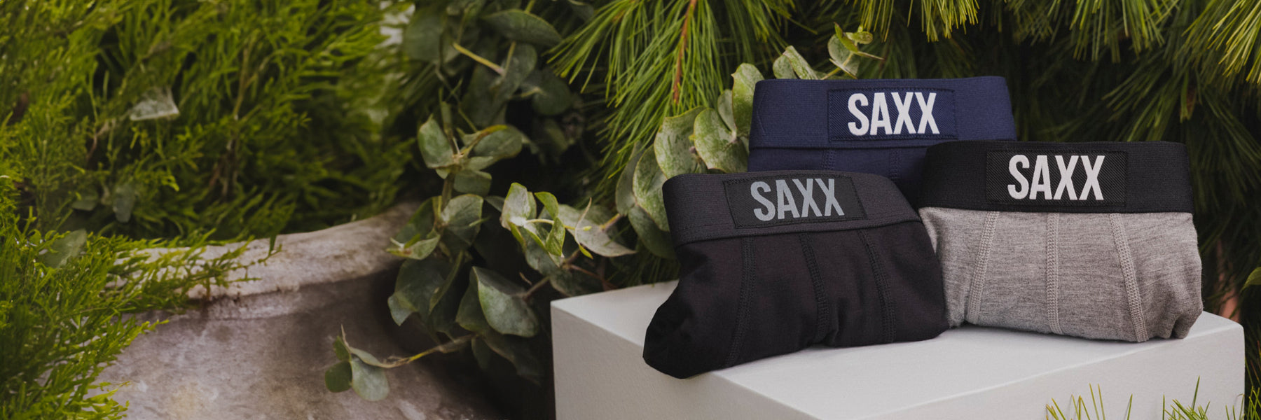 Three pair of men's underwear laying on the table with a Christmas tree background. 