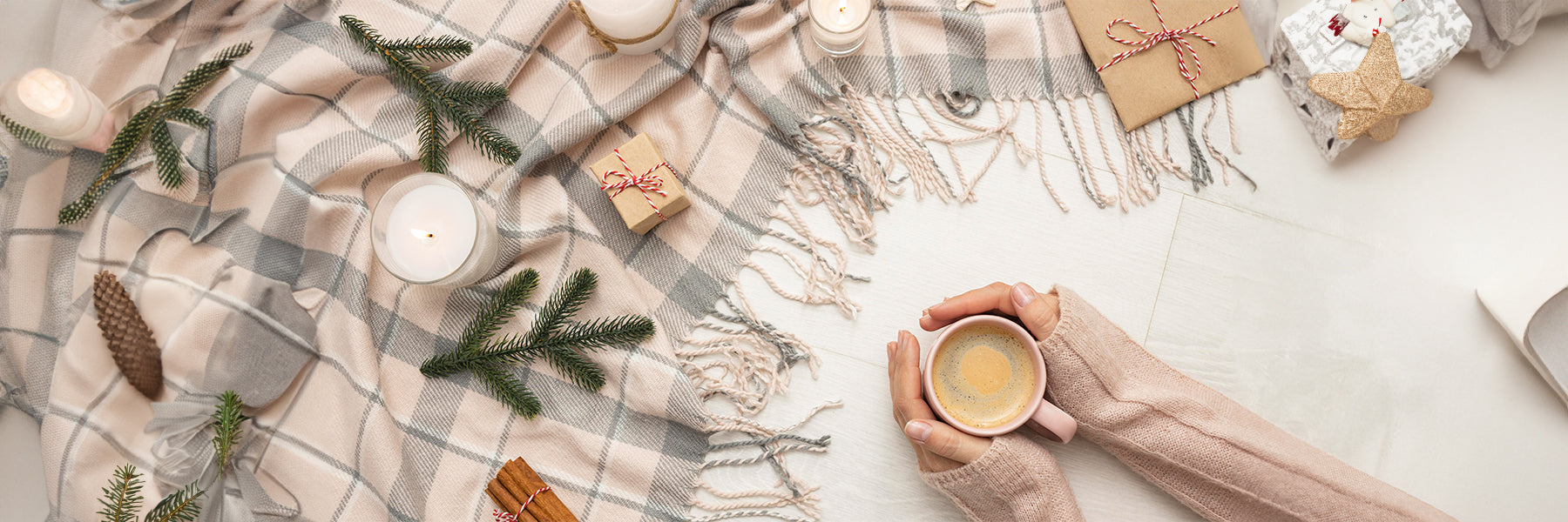 Top view of person holding mug with candles and blanket