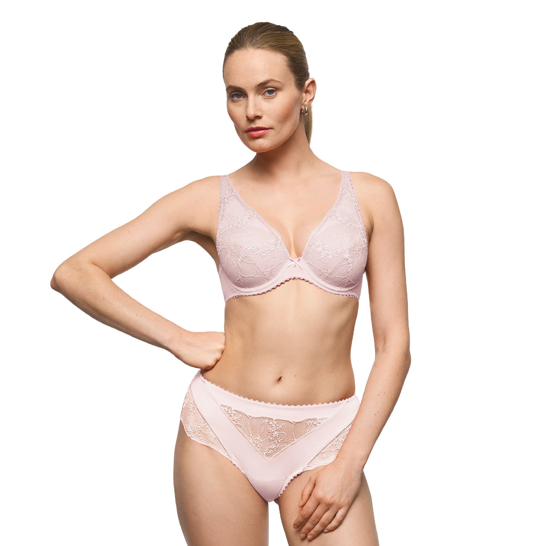 Model wearing a blush pink embroidered plunge bra and matching briefs with delicate floral lace and a feminine silhouette.