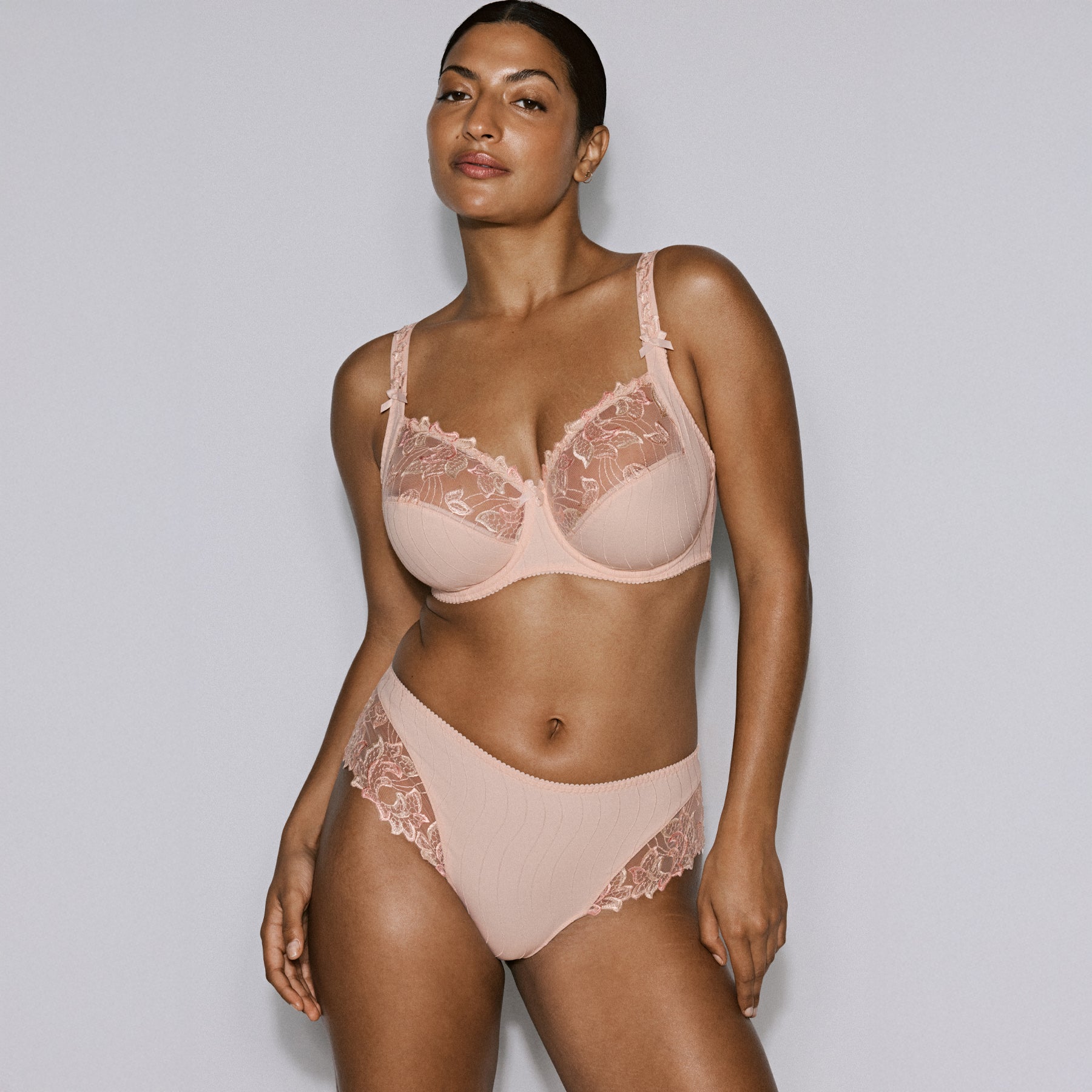 Model wearing a blush embroidered underwire bra with matching briefs, showcasing a supportive fit and elegant lace detailing.