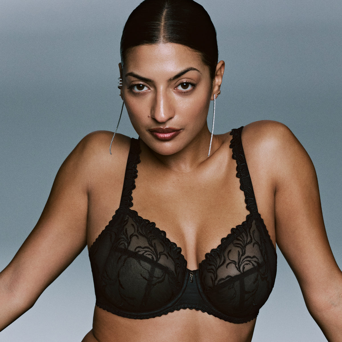 Model wearing the black PrimaDonna Solisse Full Cup Bra featuring sheer floral embroidered cups and decorative straps.