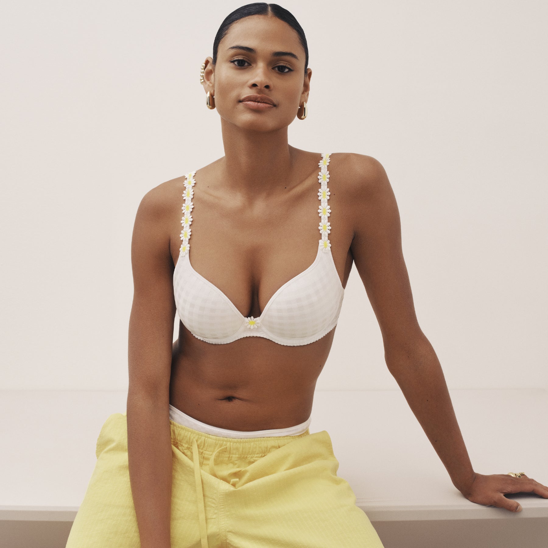 Front-facing model wearing an ivory underwire bra with floral straps, paired with soft yellow lounge pants.