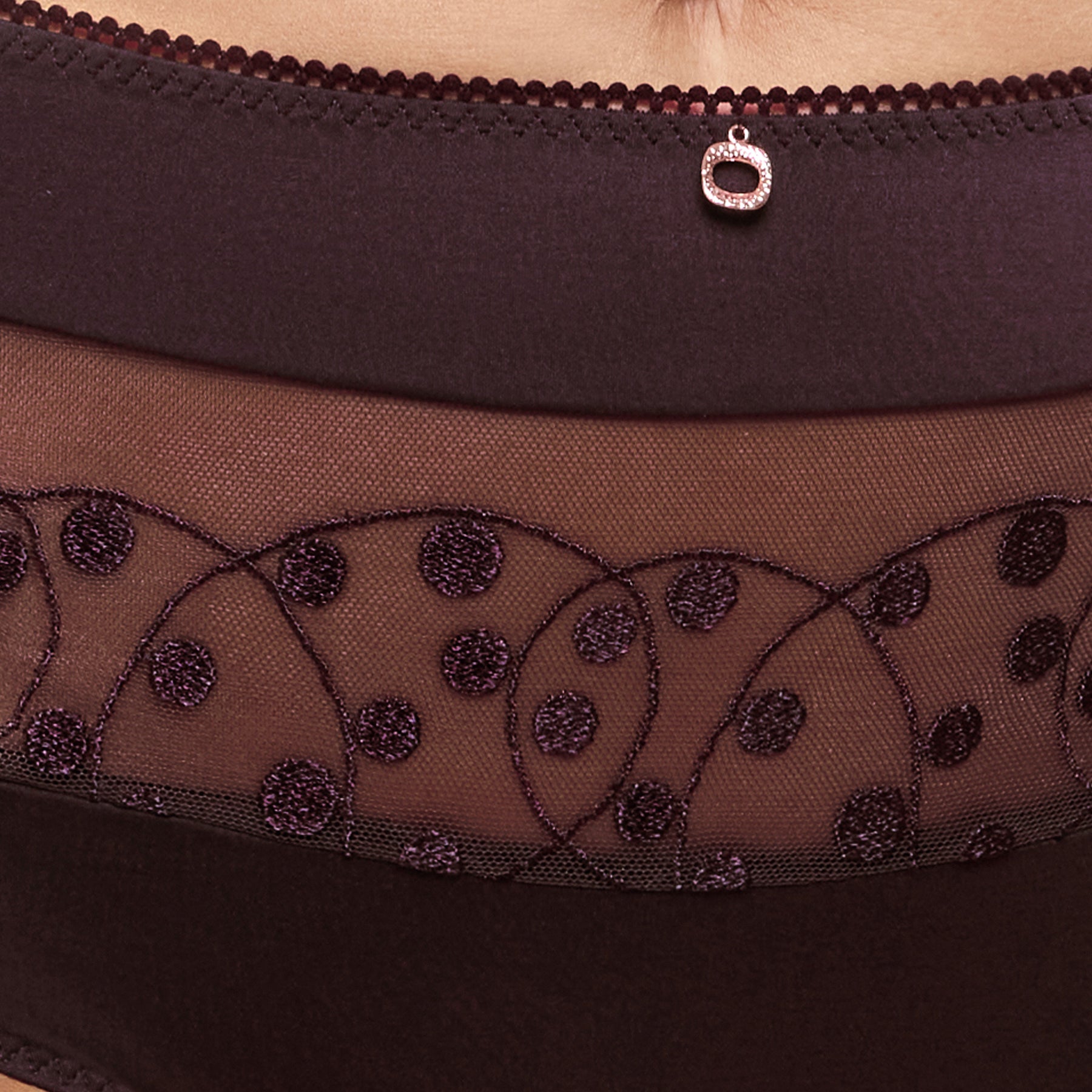 Close-up of amethyst purple high-waist panties with sheer embroidered mesh, dotted detailing and a gold charm.