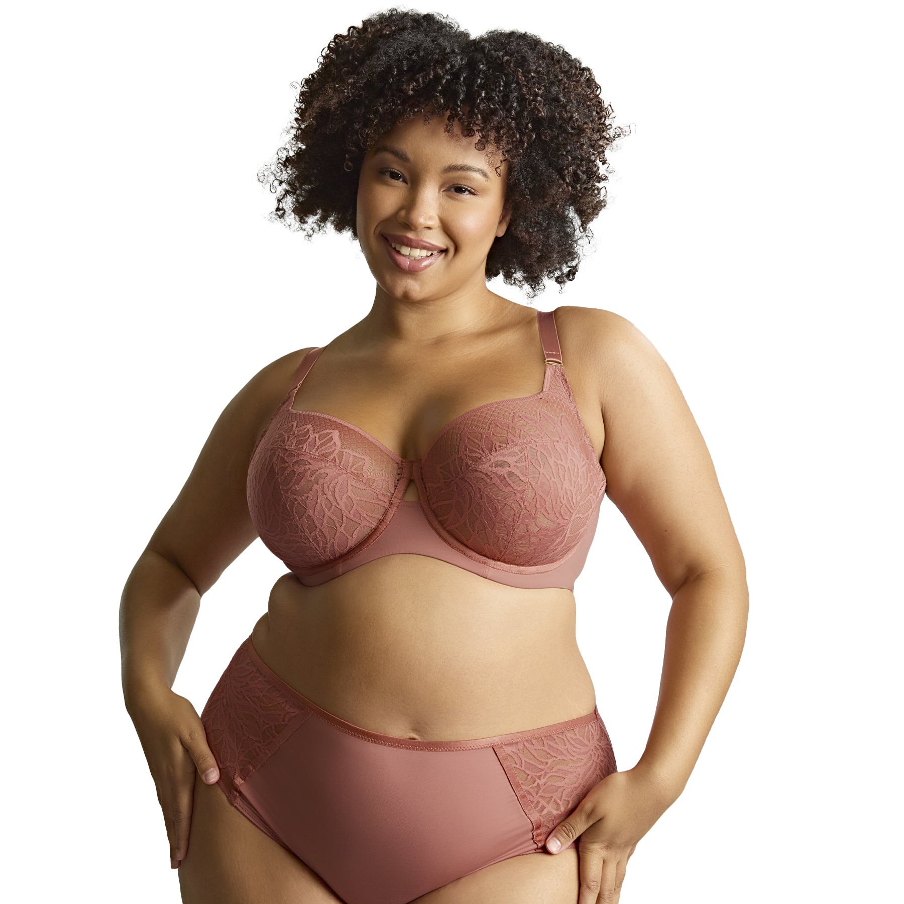 Plus-size model in sienna rose lace bra and matching brief, posing confidently against white background.