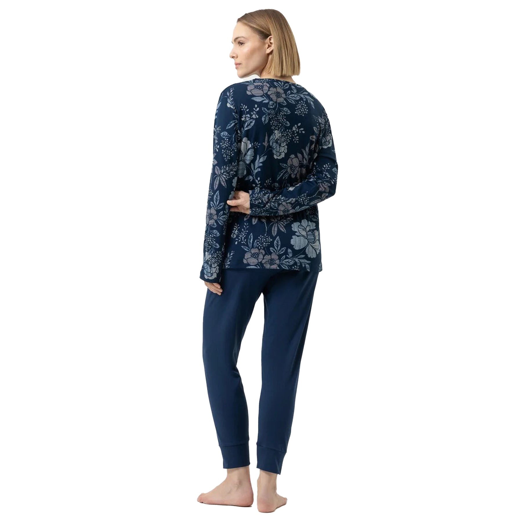 Back view of woman wearing navy blue pajama set with floral top and plain pants.