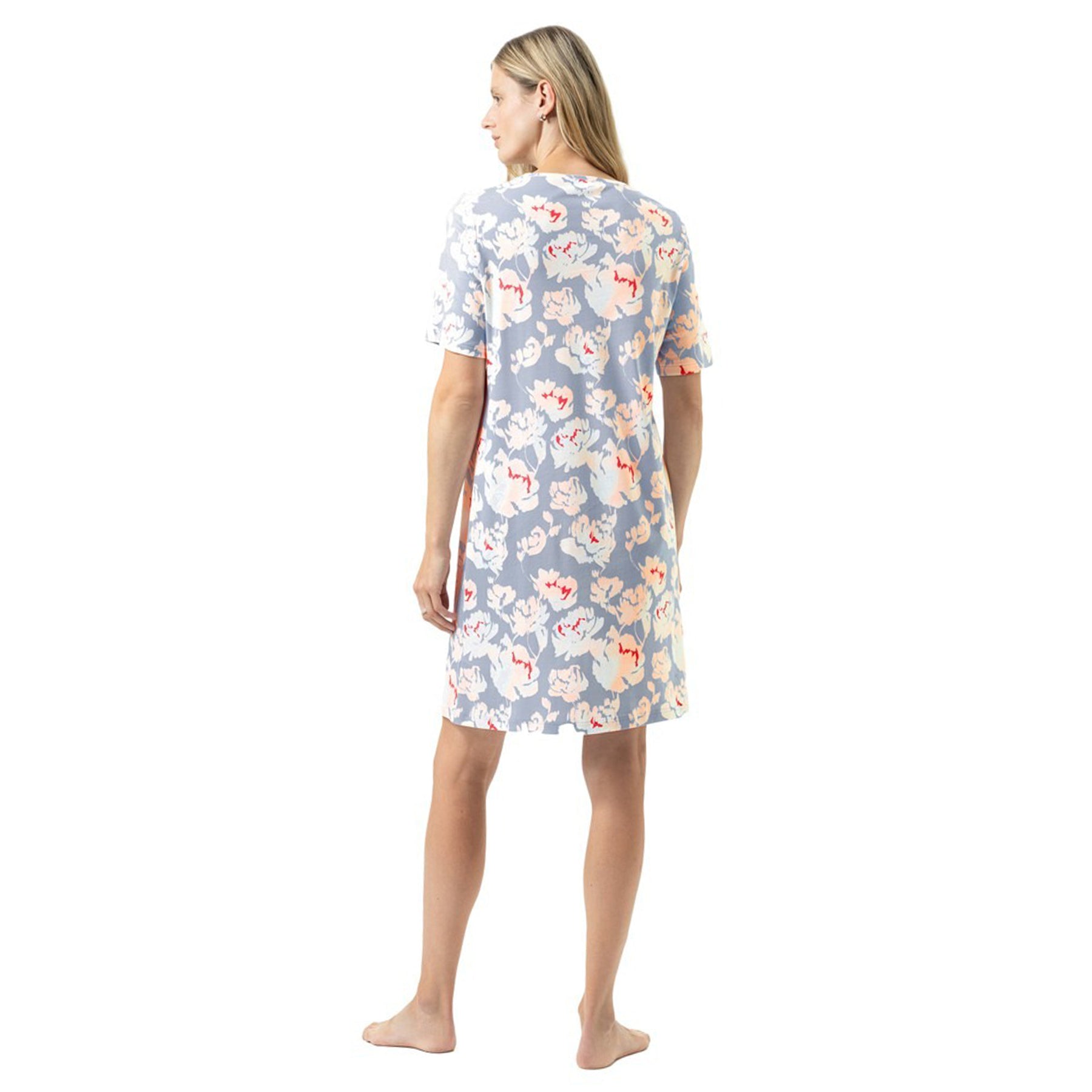 Back view of a woman wearing a knee-length floral nightdress with short sleeves, soft blue base and delicate peach-and-ivory floral pattern.