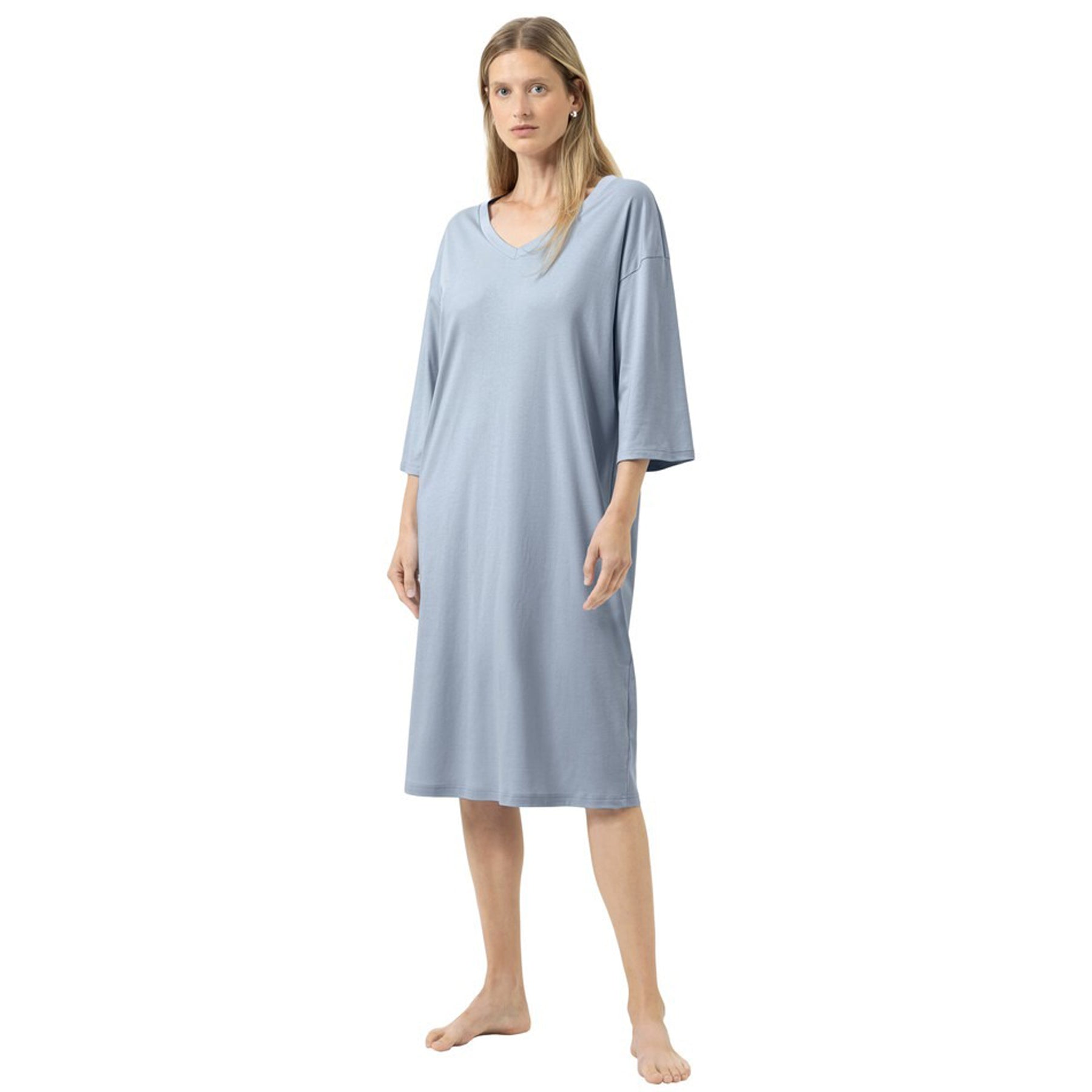 Woman wearing a knee-length nightdress in soft blue with a relaxed fit, V-neckline, and elbow-length sleeves, front view on a white background.