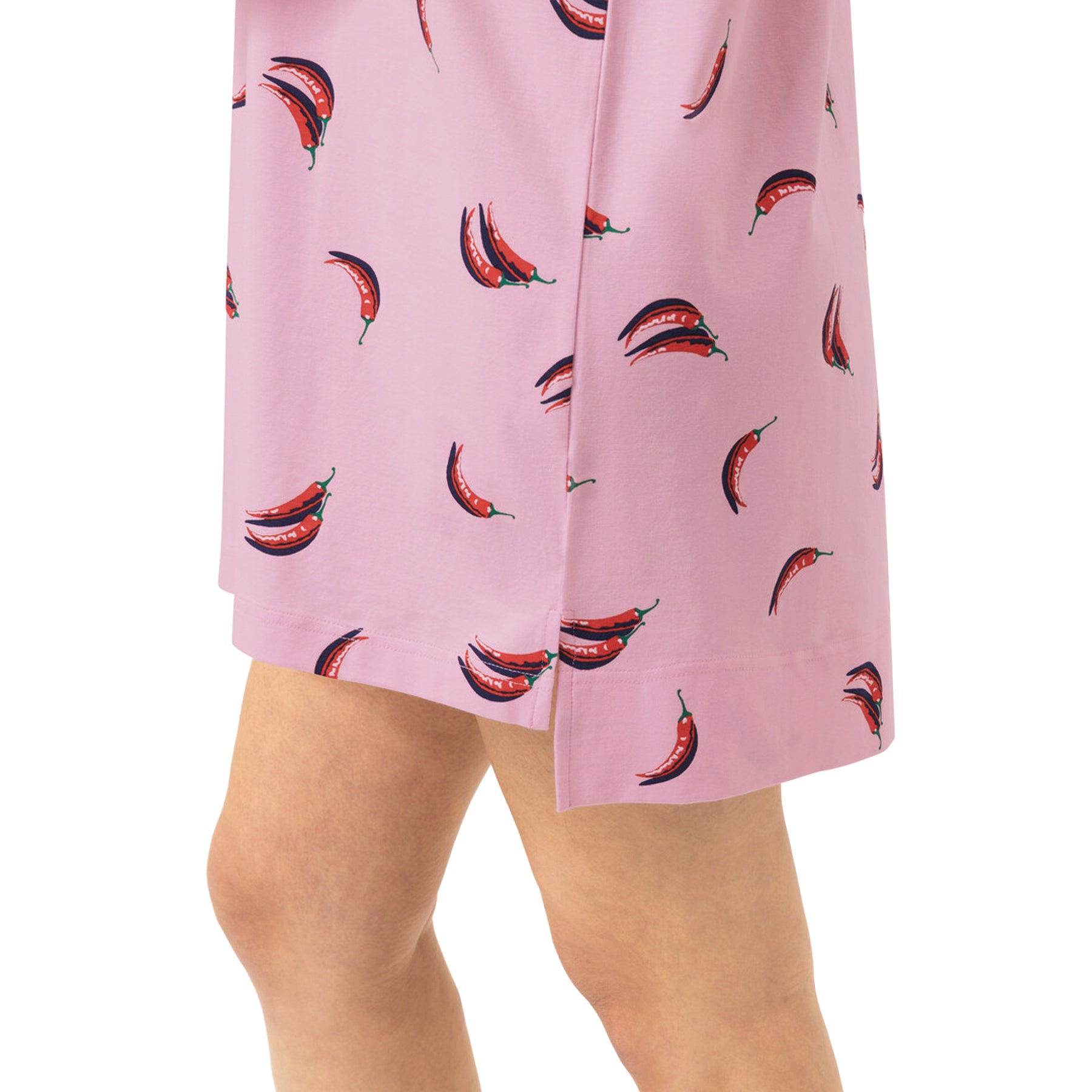 Close-up of pink sleep shirt showing the playful red chili pepper print and small side slit at the hem.