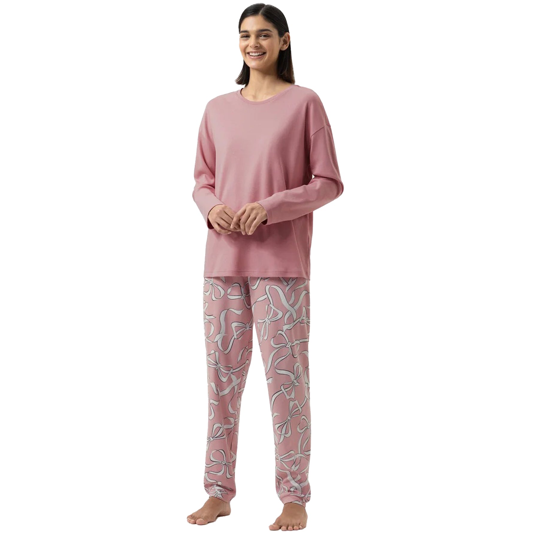 Woman wearing pink long-sleeve top with printed ribbon-pattern pyjama pants.