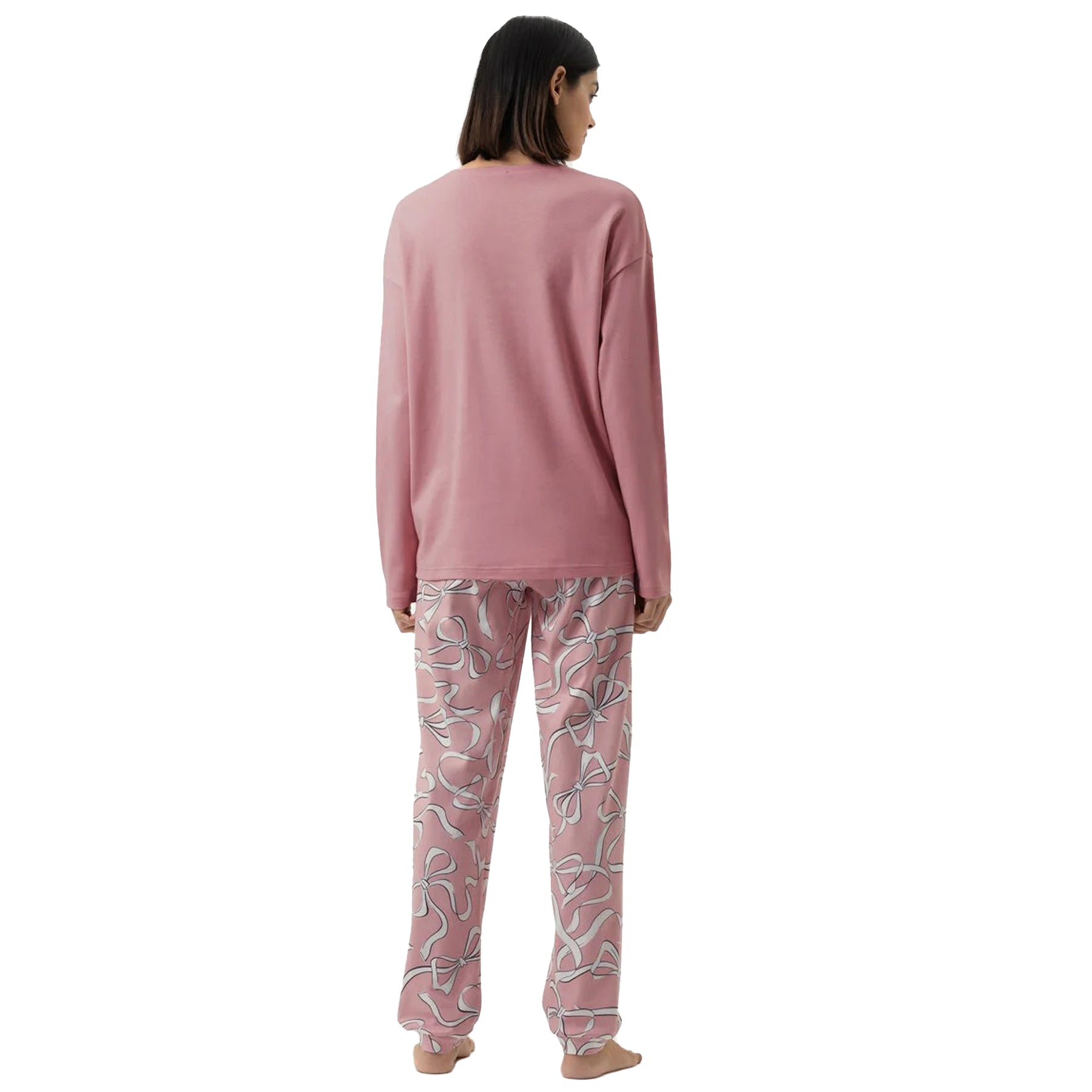 Back view of woman wearing pink long-sleeve top and ribbon print pyjama pants.