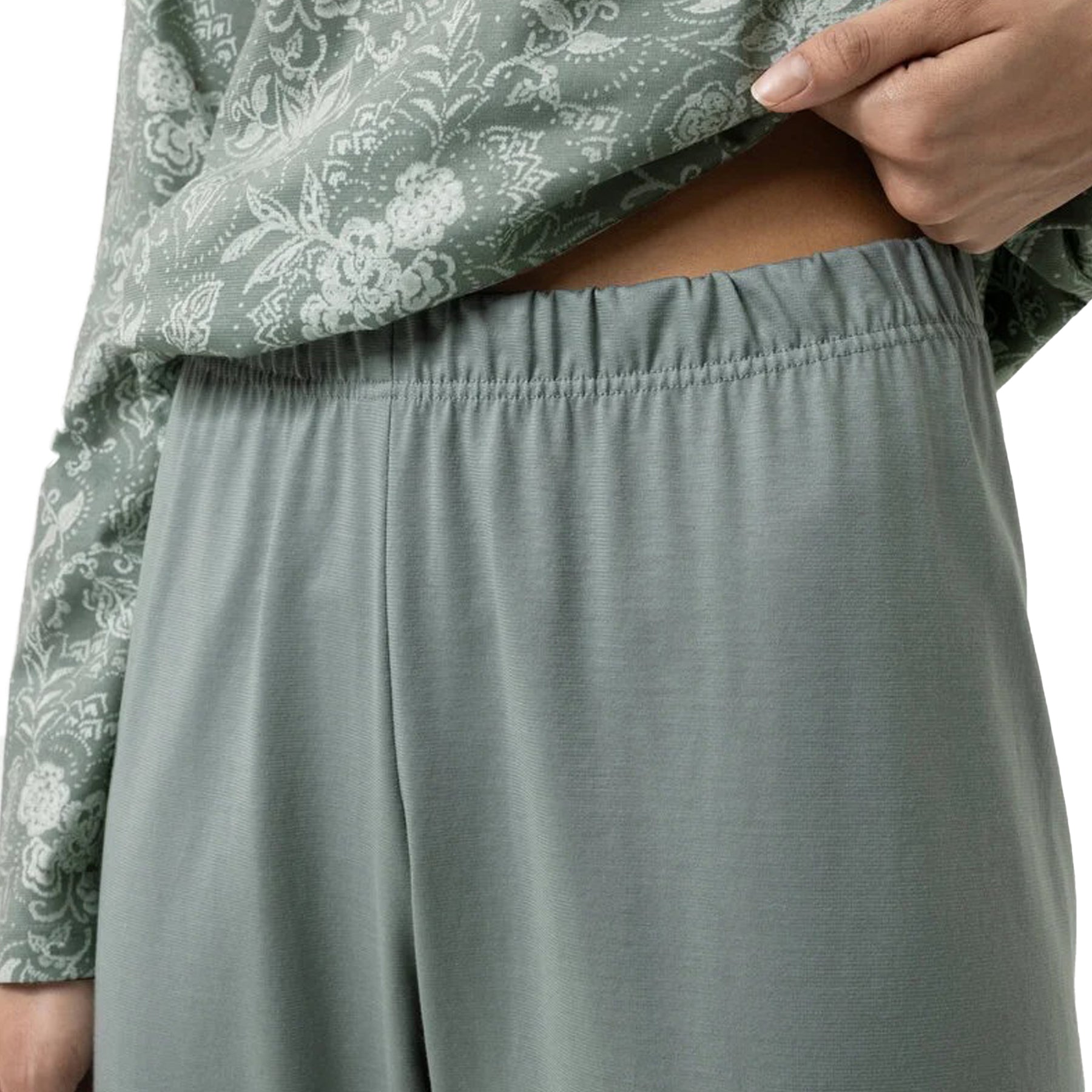 Close-up of elastic waistband on sage green pyjama pants with floral top detail.