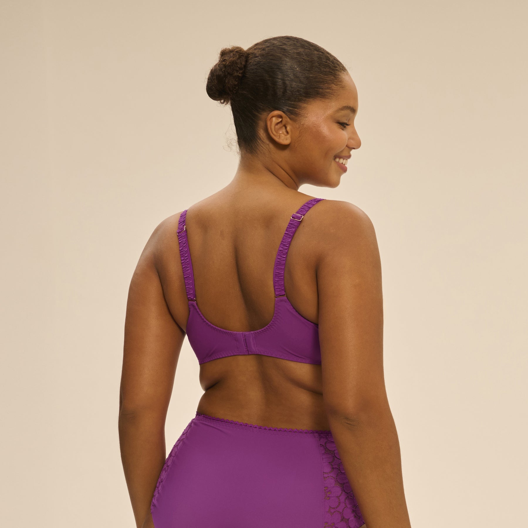 Back view of model wearing Simone Pérèle Oisive Full Cup Bra in fuchsia, showing smooth band and adjustable straps.