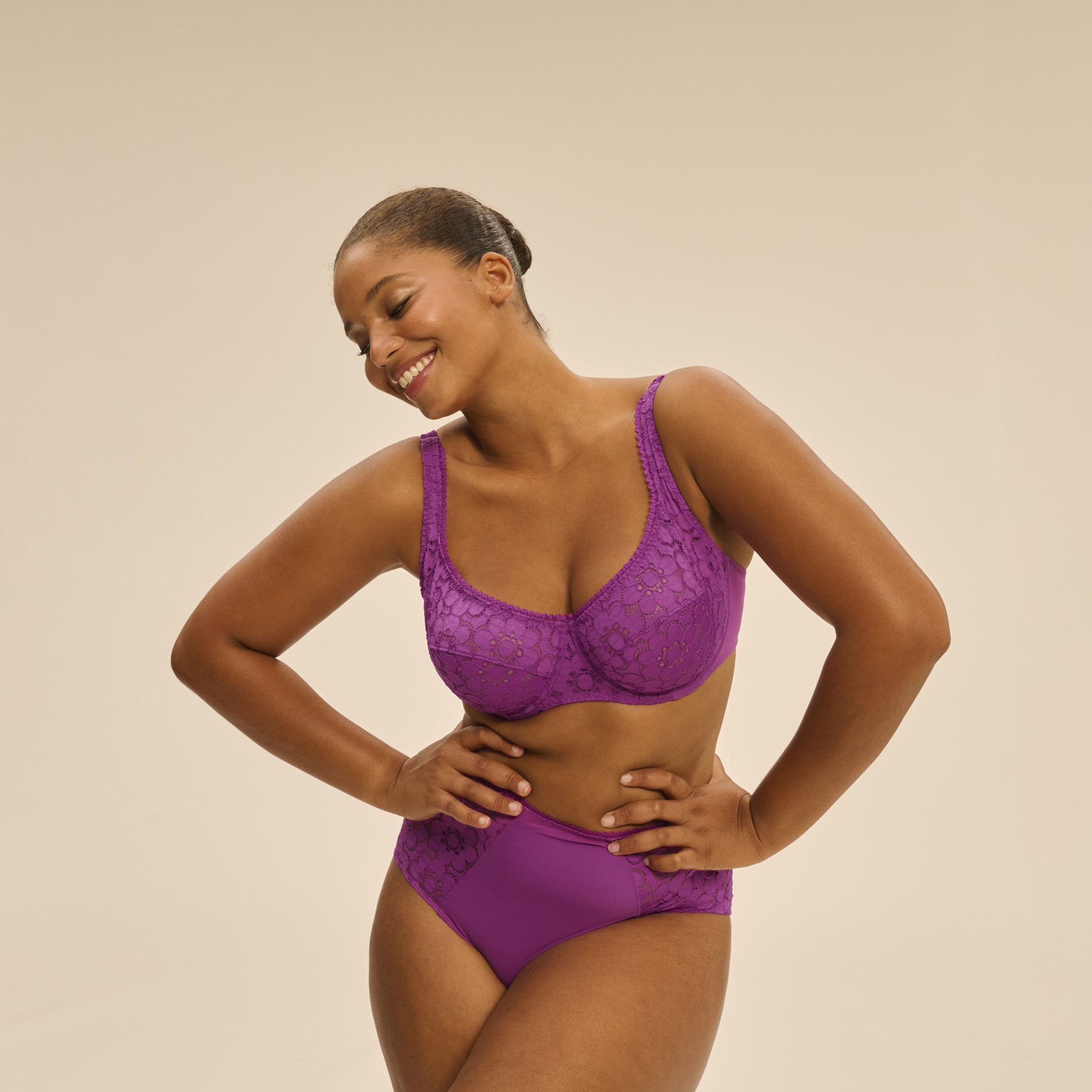 Model in Simone Pérèle Oisive Full Cup Bra and matching high-waisted brief in fuchsia, smiling with hands on hips.