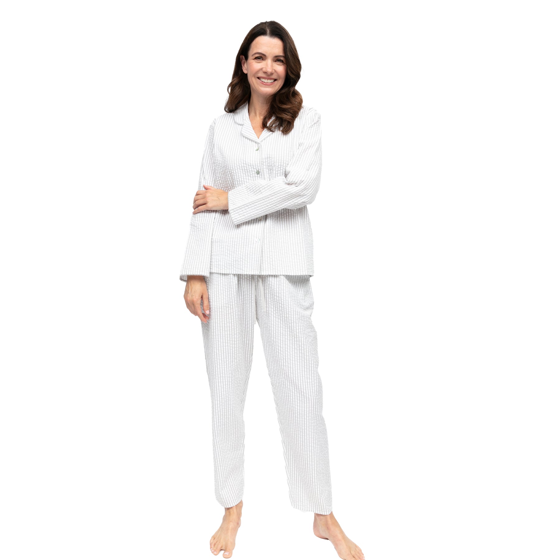 Woman modeling striped long-sleeve pyjama set standing on white background.