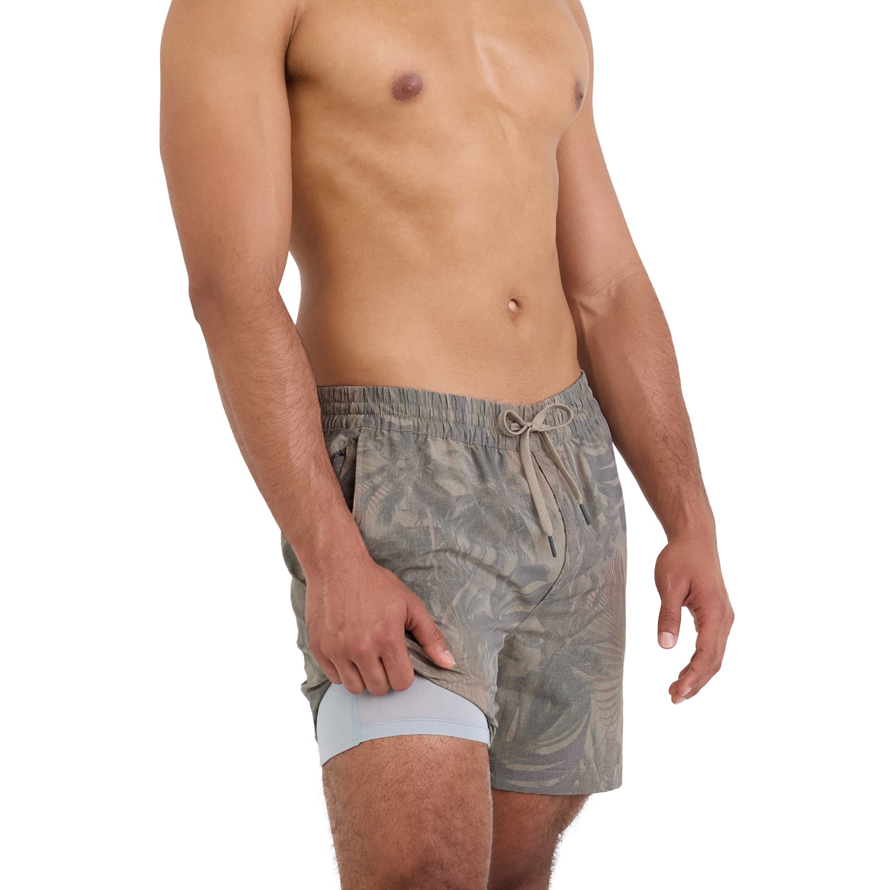 Man wearing palm print swim shorts with built-in light grey compression liner, shown on a white background