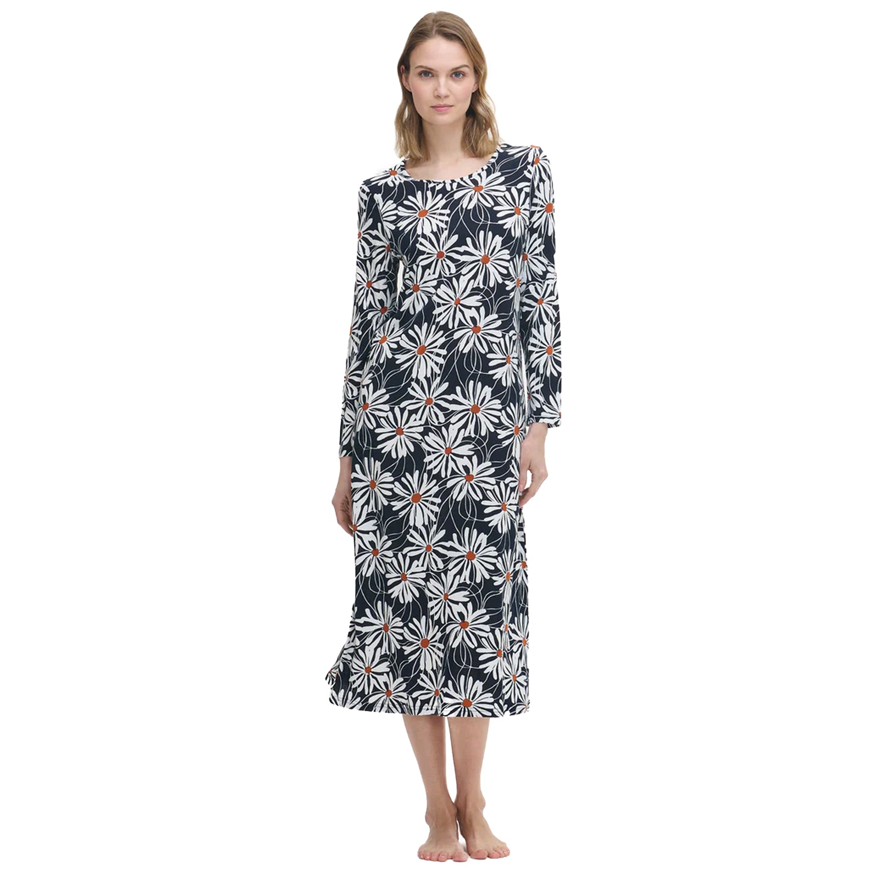Woman wearing a long navy nightdress with large white daisy floral print and orange centres, standing barefoot against a white background.