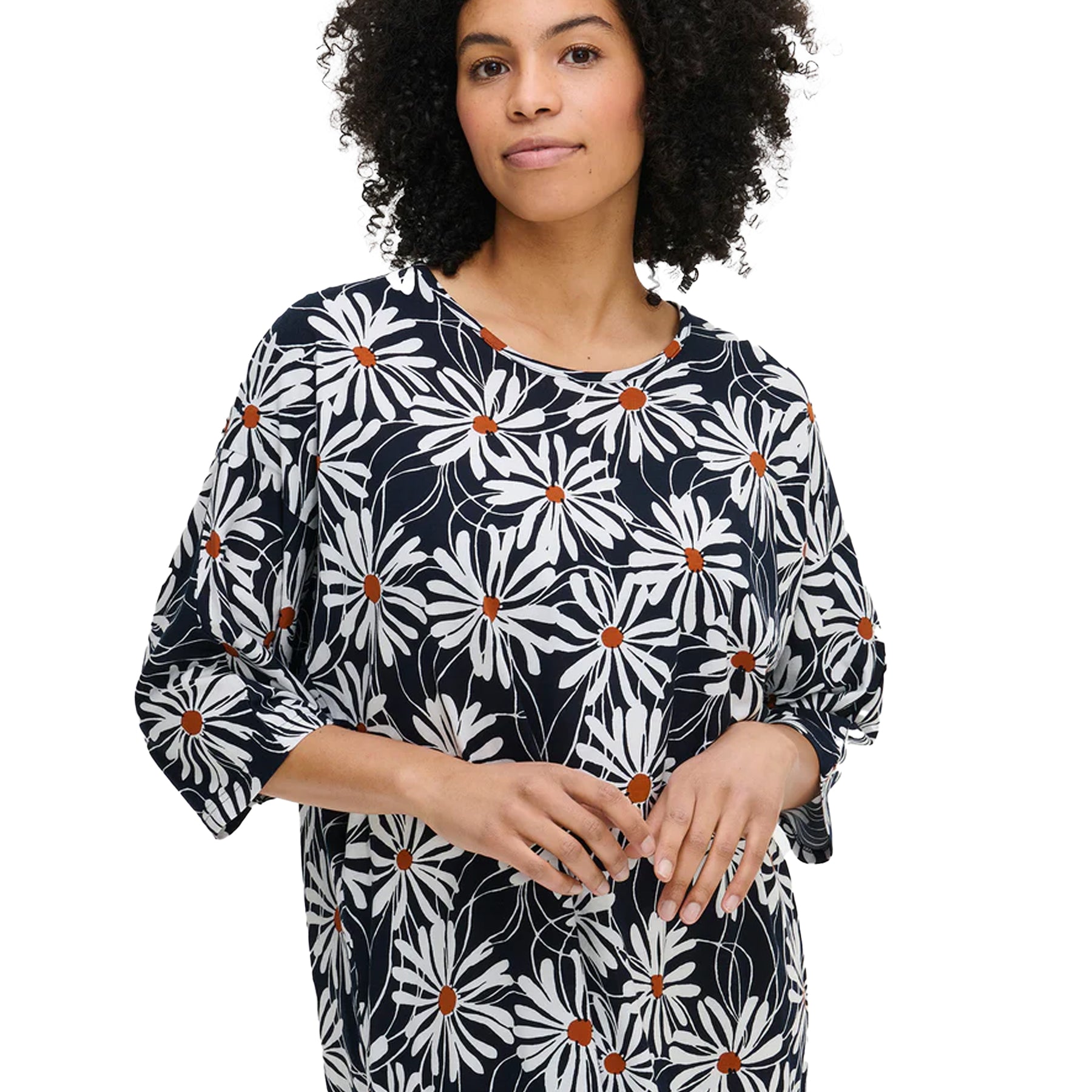 Woman wearing a navy daisy-print nightdress with relaxed sleeves, showing the round neckline and soft cotton fabric detail.