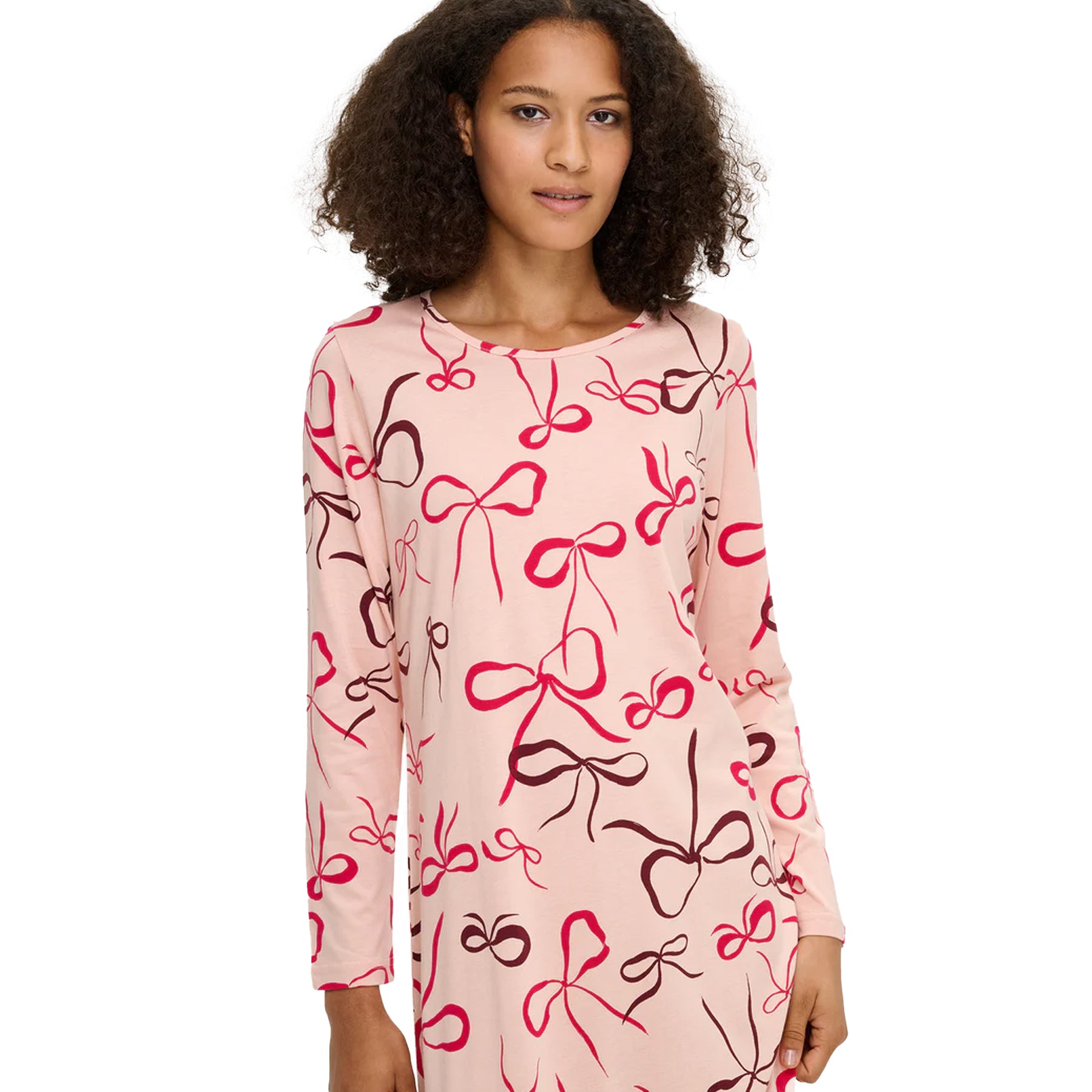 Woman wearing a pink long-sleeve nightdress with multicolour bow pattern and round neckline detail.