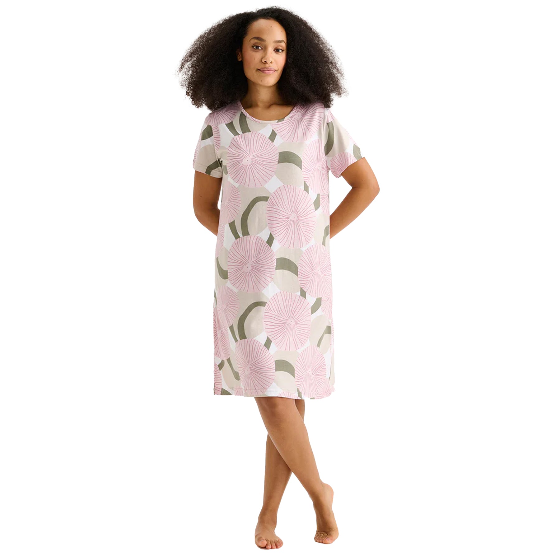 Woman wearing a pink circular floral print short-sleeve chemise nightdress with relaxed knee-length silhouette.