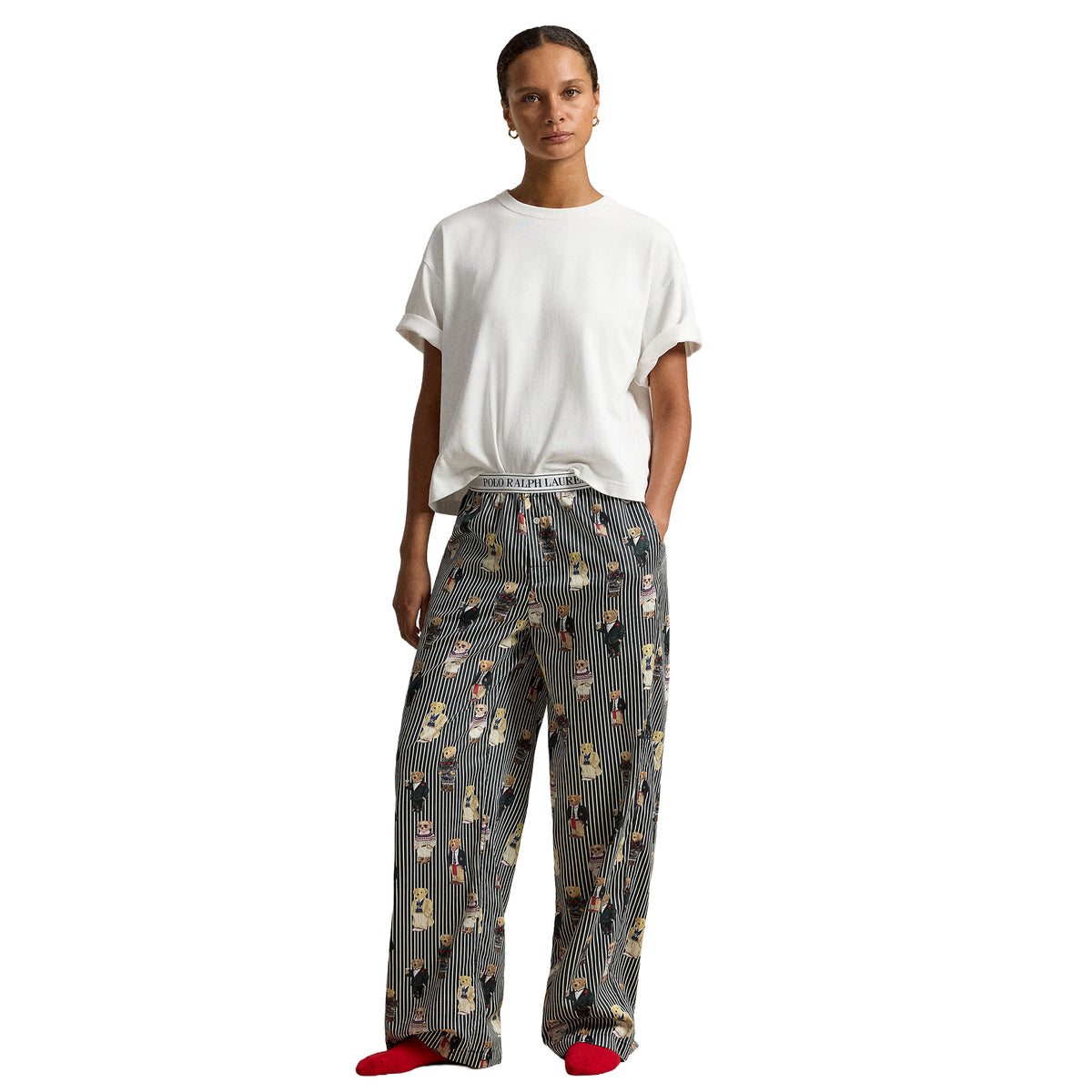 Model wearing Polo Ralph Lauren wide-leg pajama pants with black and white pinstripes, an all-over Polo Bear print, side pockets, and a branded elastic waistband.