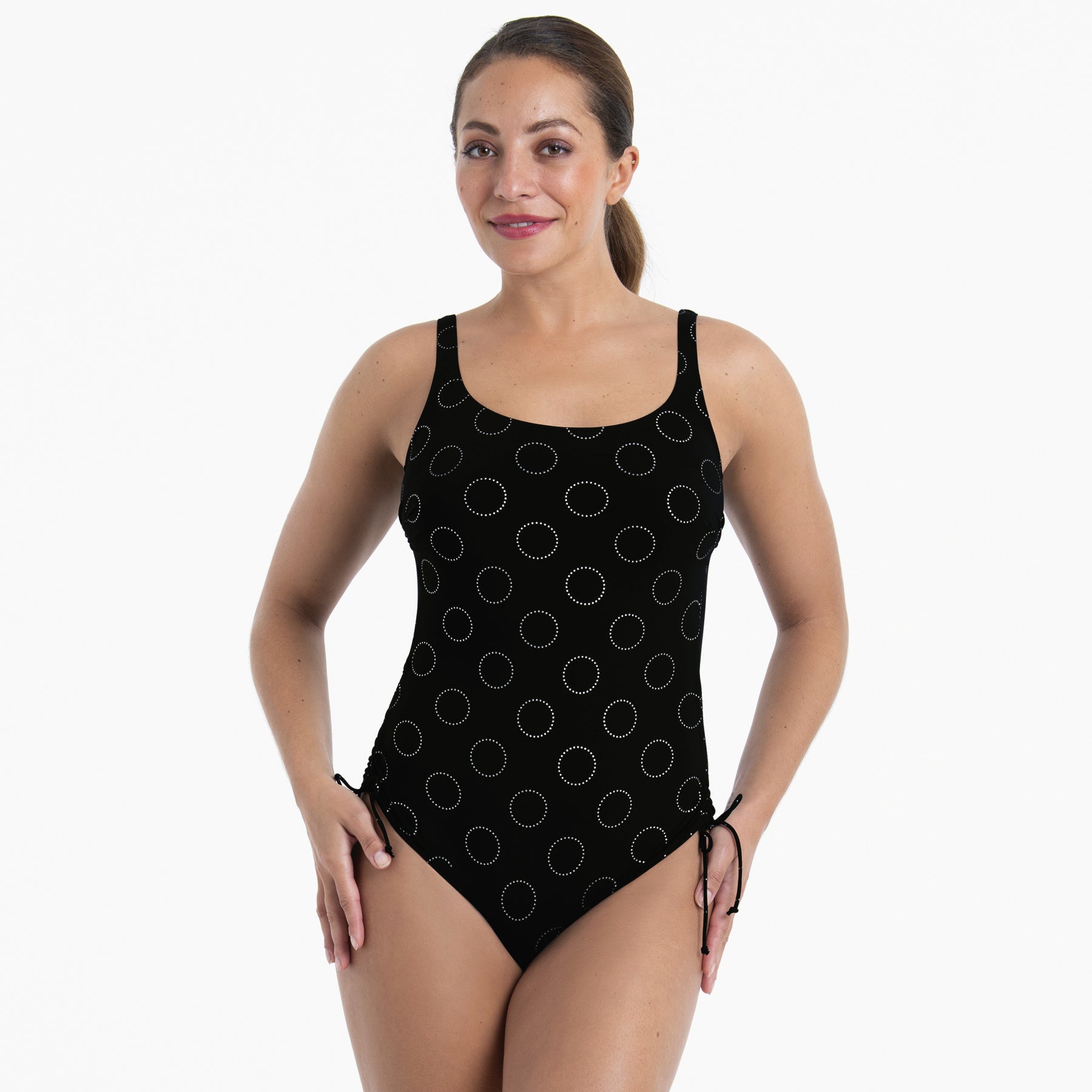 Front view of black one-piece swimsuit featuring dotted circle pattern and adjustable side ties