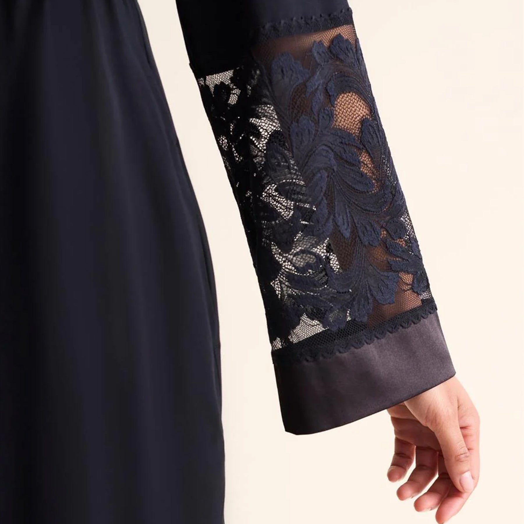 Navy blue sleeve with floral lace detail on a plain background