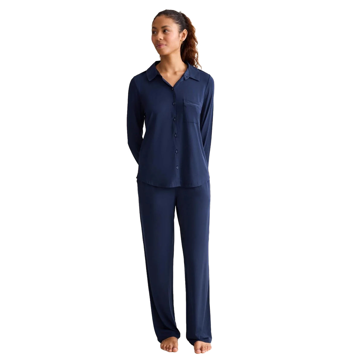 Model wearing an Ink Navy long-sleeve pyjama set featuring a button-front collared top with a chest pocket and matching relaxed-fit full-length pants.
