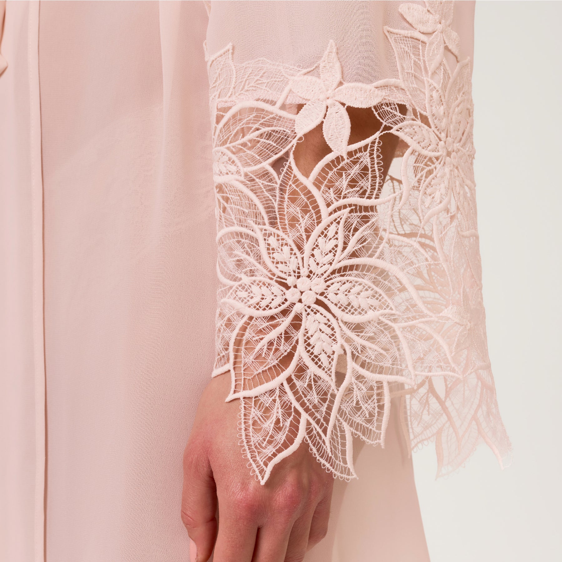 Close-up of blush robe sleeve showcasing intricate floral lace embroidery with sheer finish