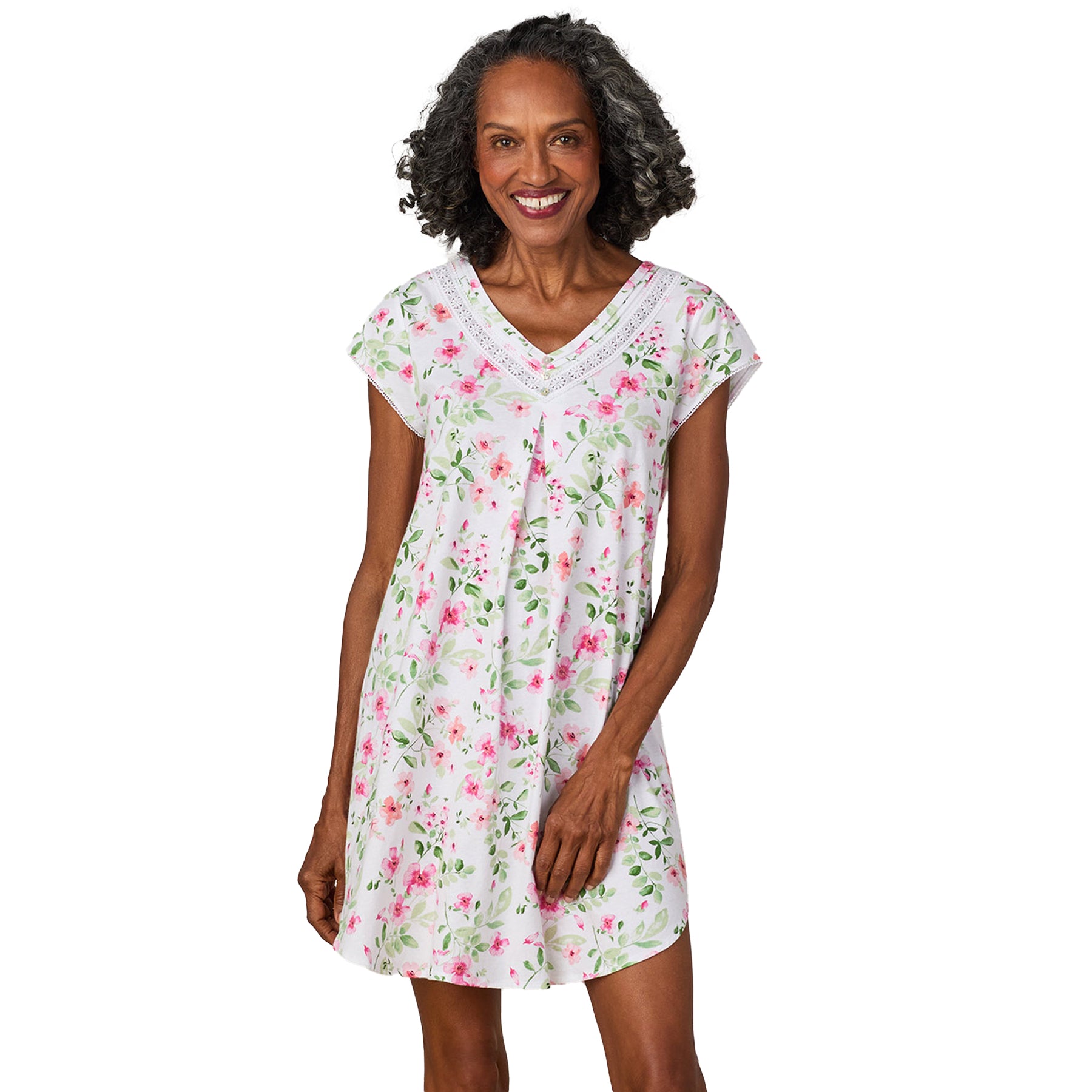 Smiling woman in a cap-sleeve white floral nightgown with a relaxed A-line fit and lace neckline detail.
