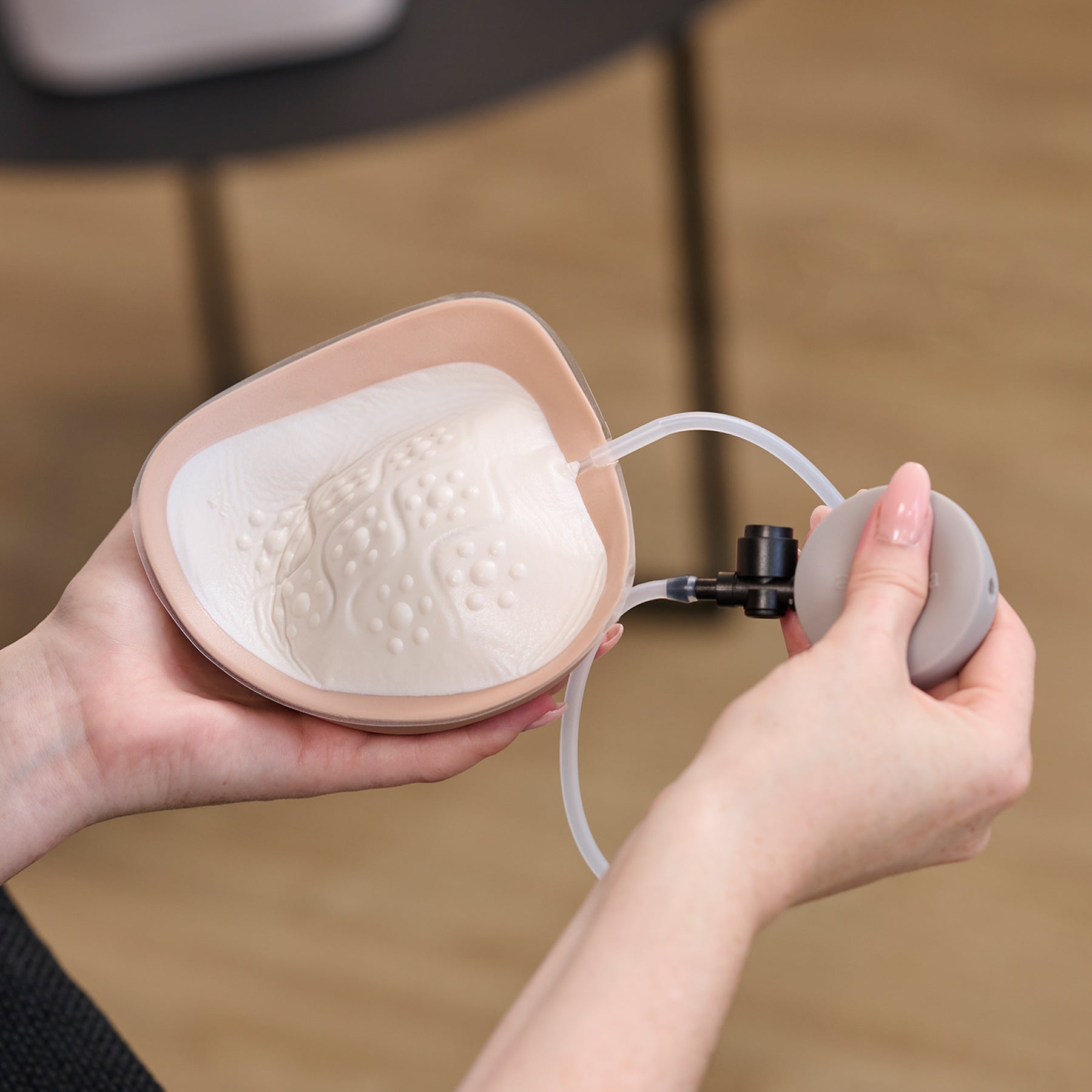 hands adjusting amoena adapt air breast prosthesis using air pump to customise volume.