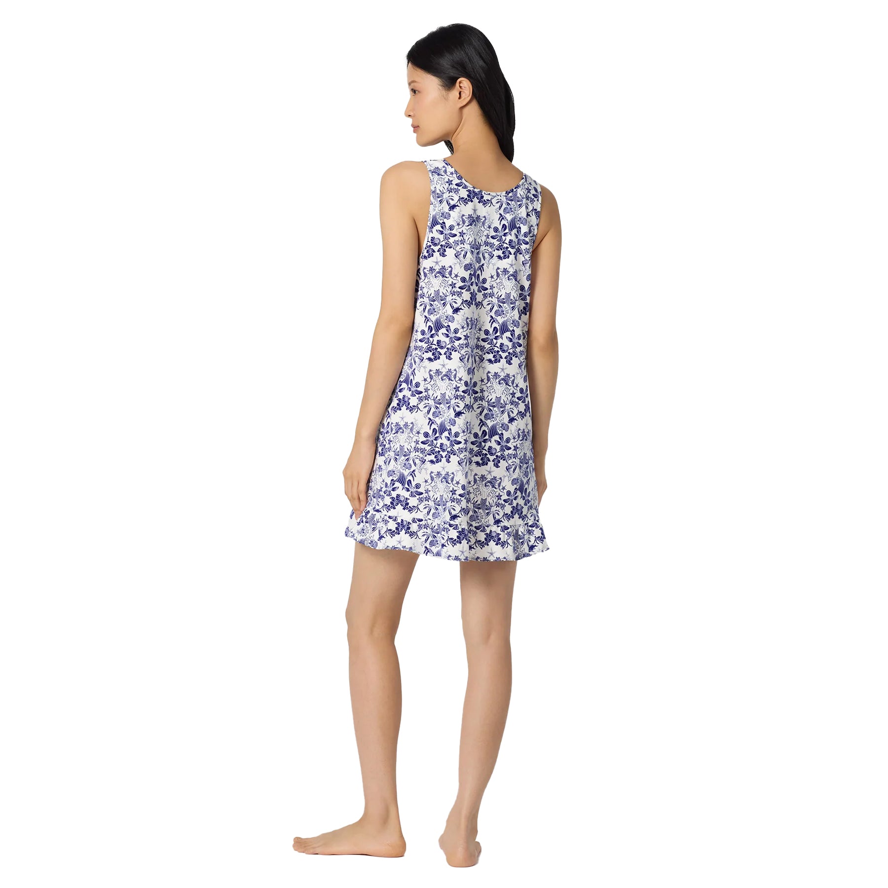 Side back view of a sleeveless white nightdress with blue seashell and floral print, designed with a relaxed silhouette and feminine ruffle hem.