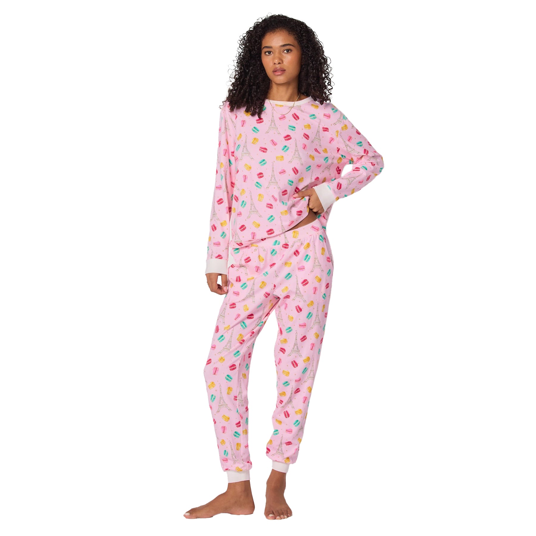 Woman wearing a pink pajama set with colorful patterns on a white background