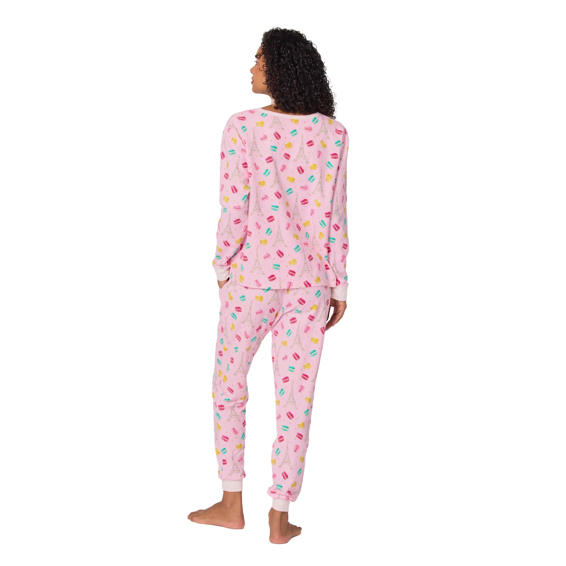 Woman wearing pink pajamas with colorful patterns on a white background