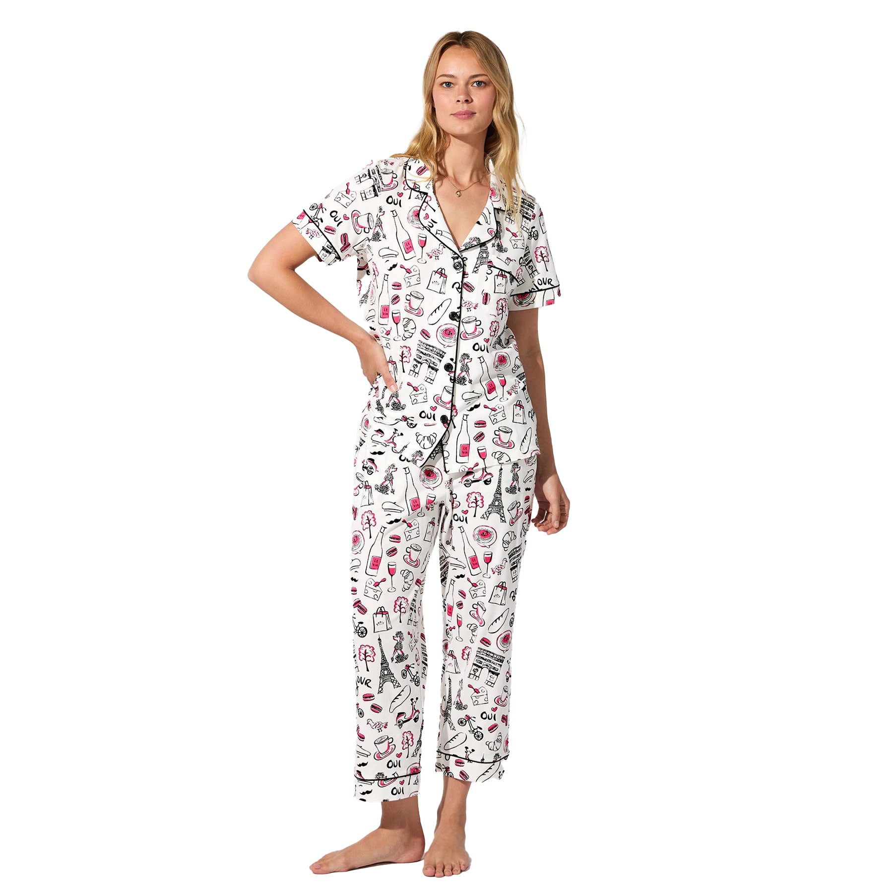 Front view of women’s Paris-themed pajama set with short-sleeve button-up top and cropped pants, featuring black piping and whimsical pink-and-black illustrations.