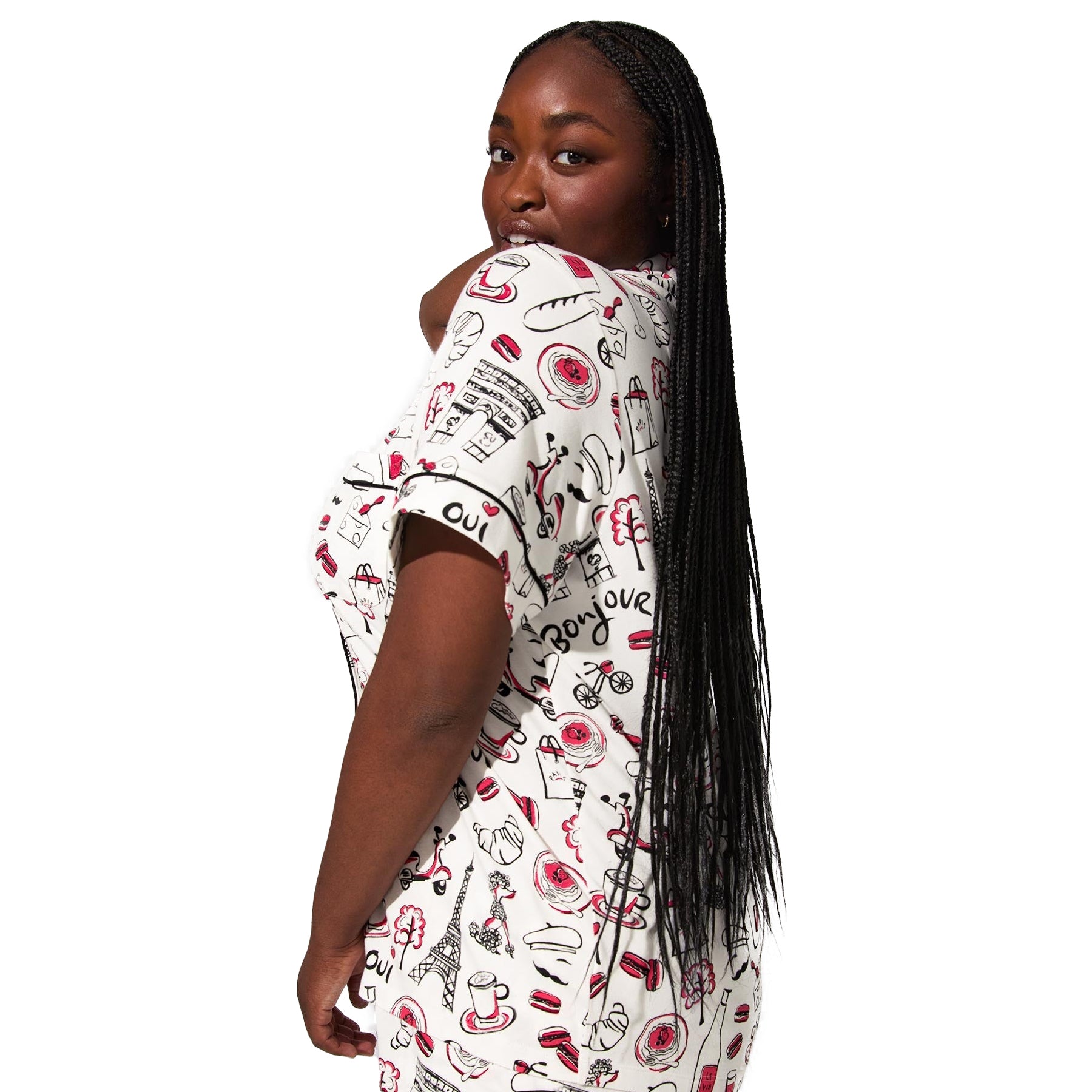 Close-up side view of plus-size model wearing Paris print short-sleeve pajama top with black piping and illustrated croissants, macarons, and Eiffel Tower.