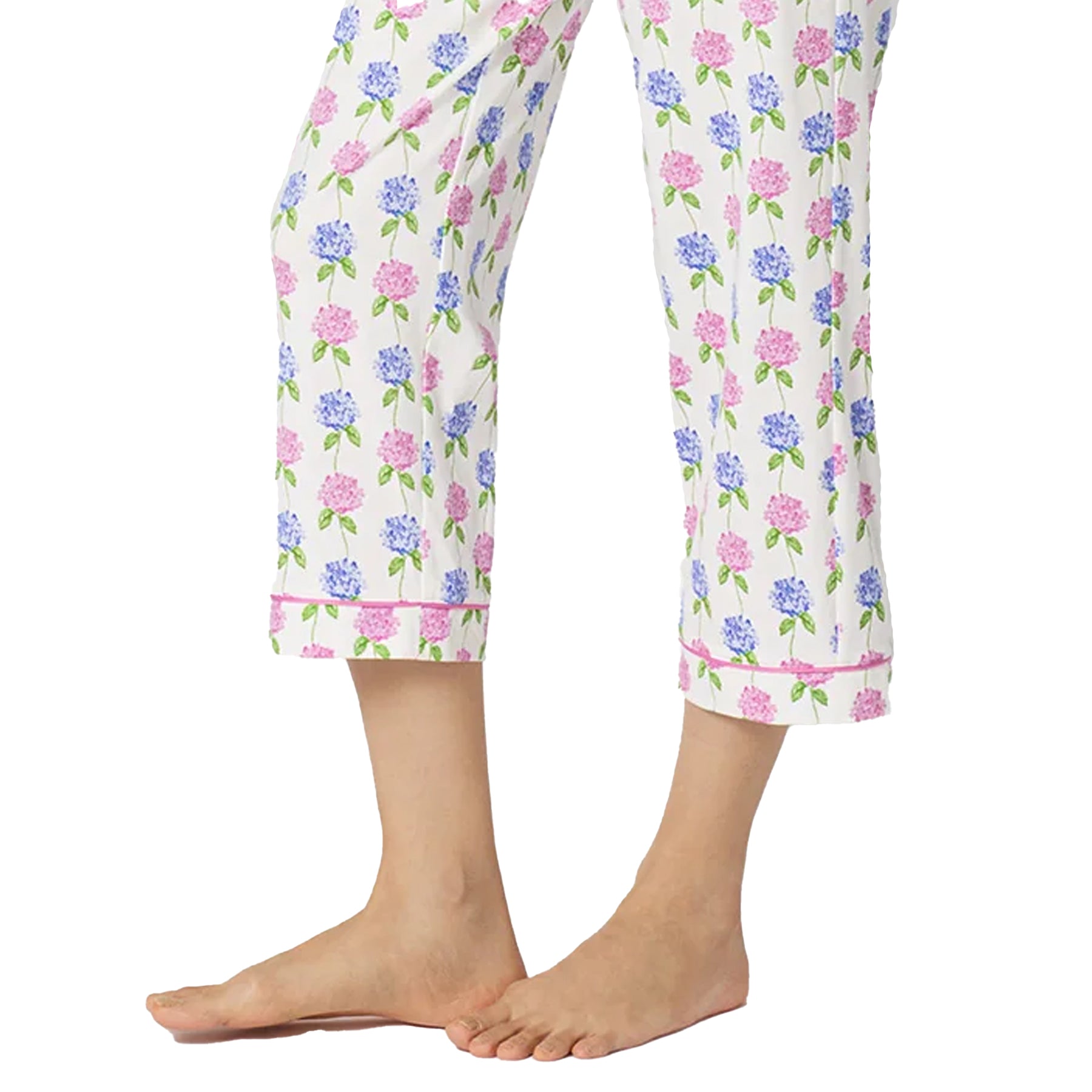 Detail of cropped white pyjama pants with pastel hydrangea floral print and pink piping trim at the hem.