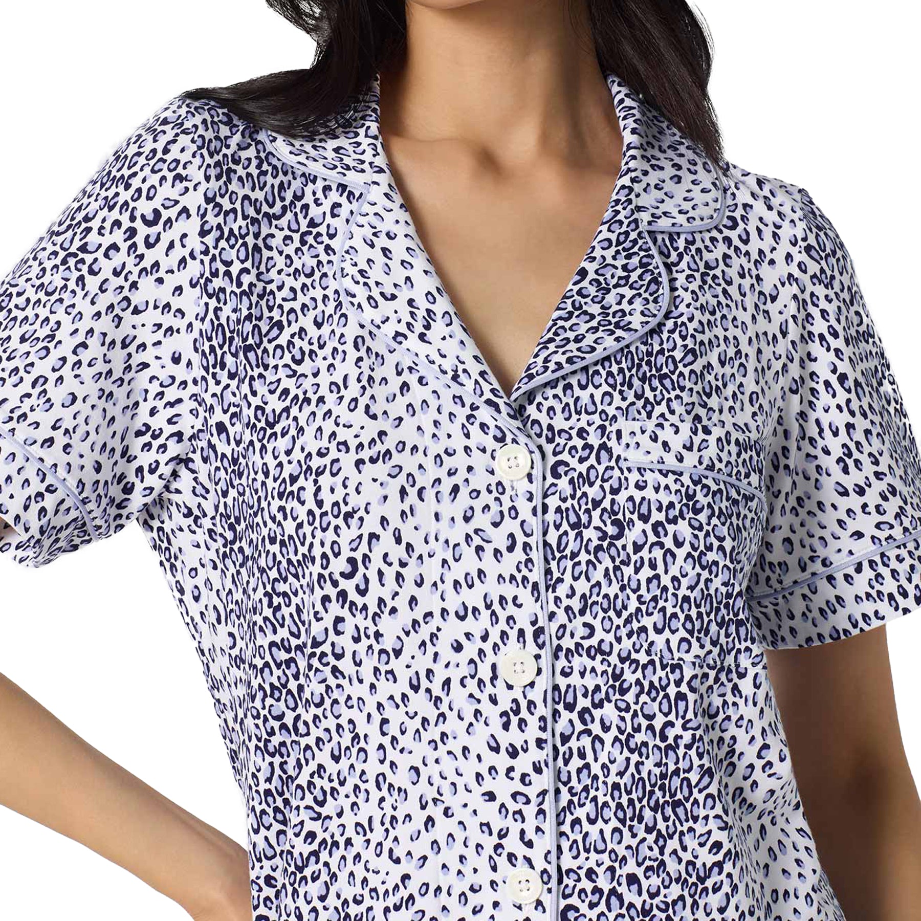 Close-up of a white and navy leopard print pyjama top with short sleeves, button-front closure, chest pocket, and contrast piping detail.